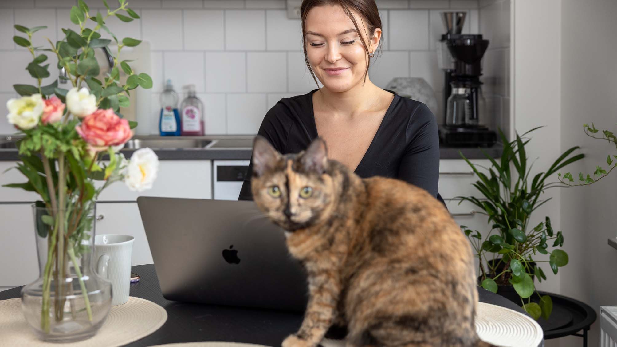 Emma sitter och jobbar vid sin dator med katt