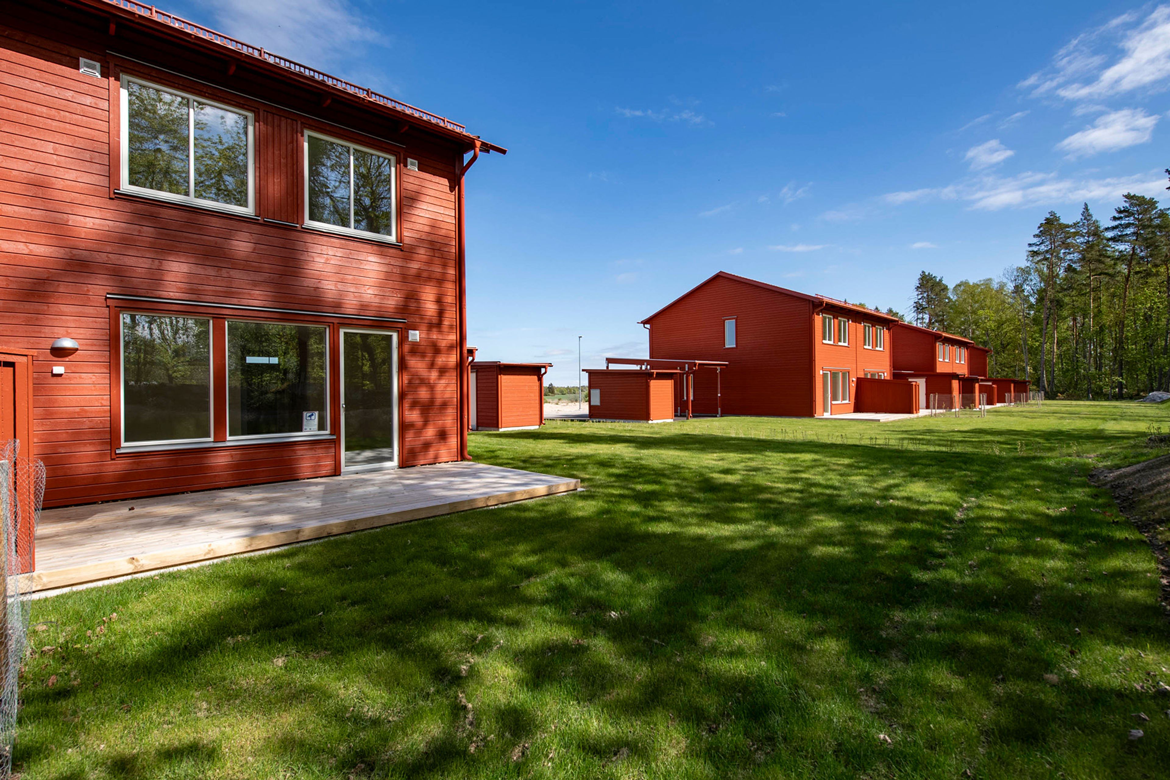 Röda parhus med uteplats och generösa gräsmattor