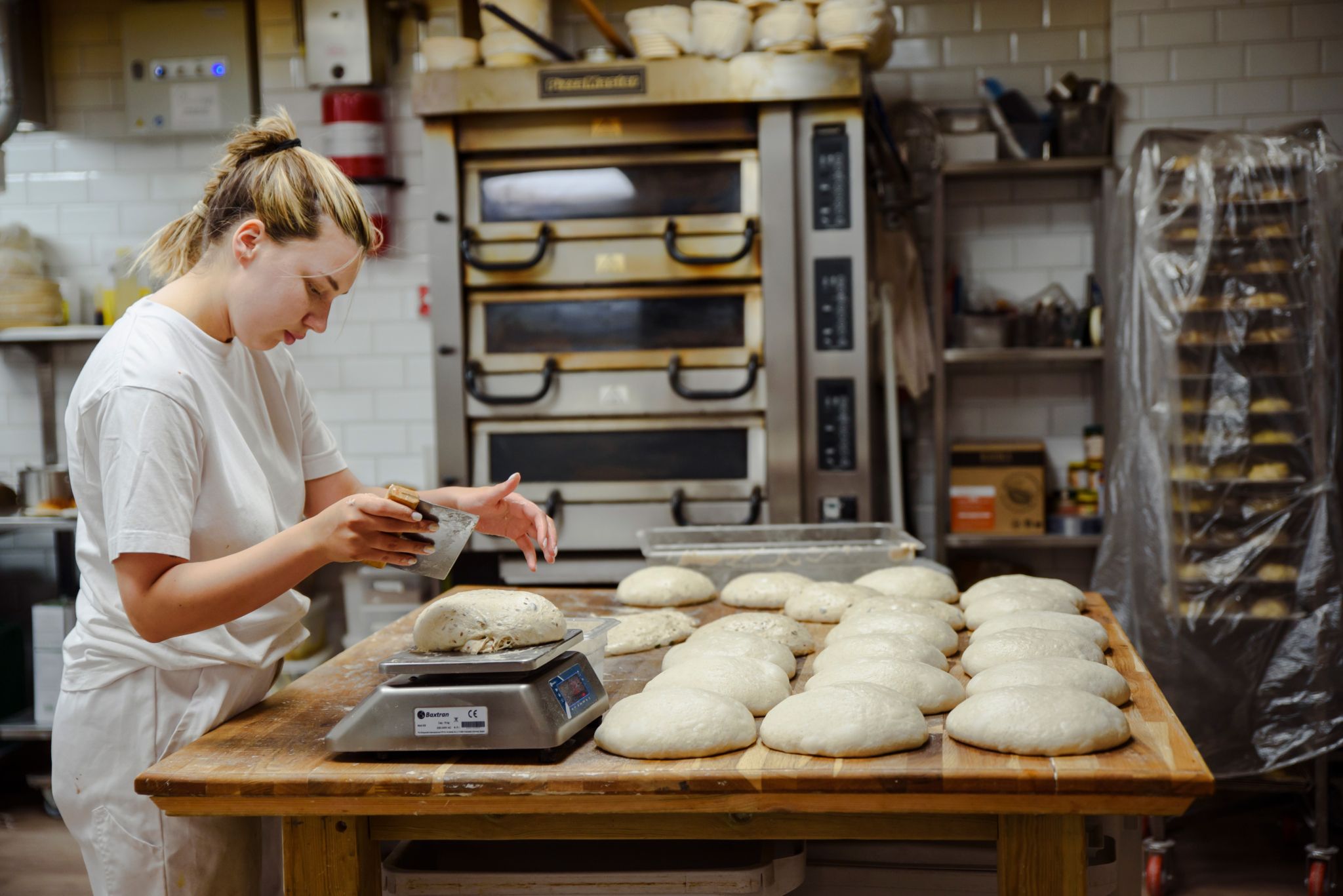 Kvinne som står ved et bord og baker brød