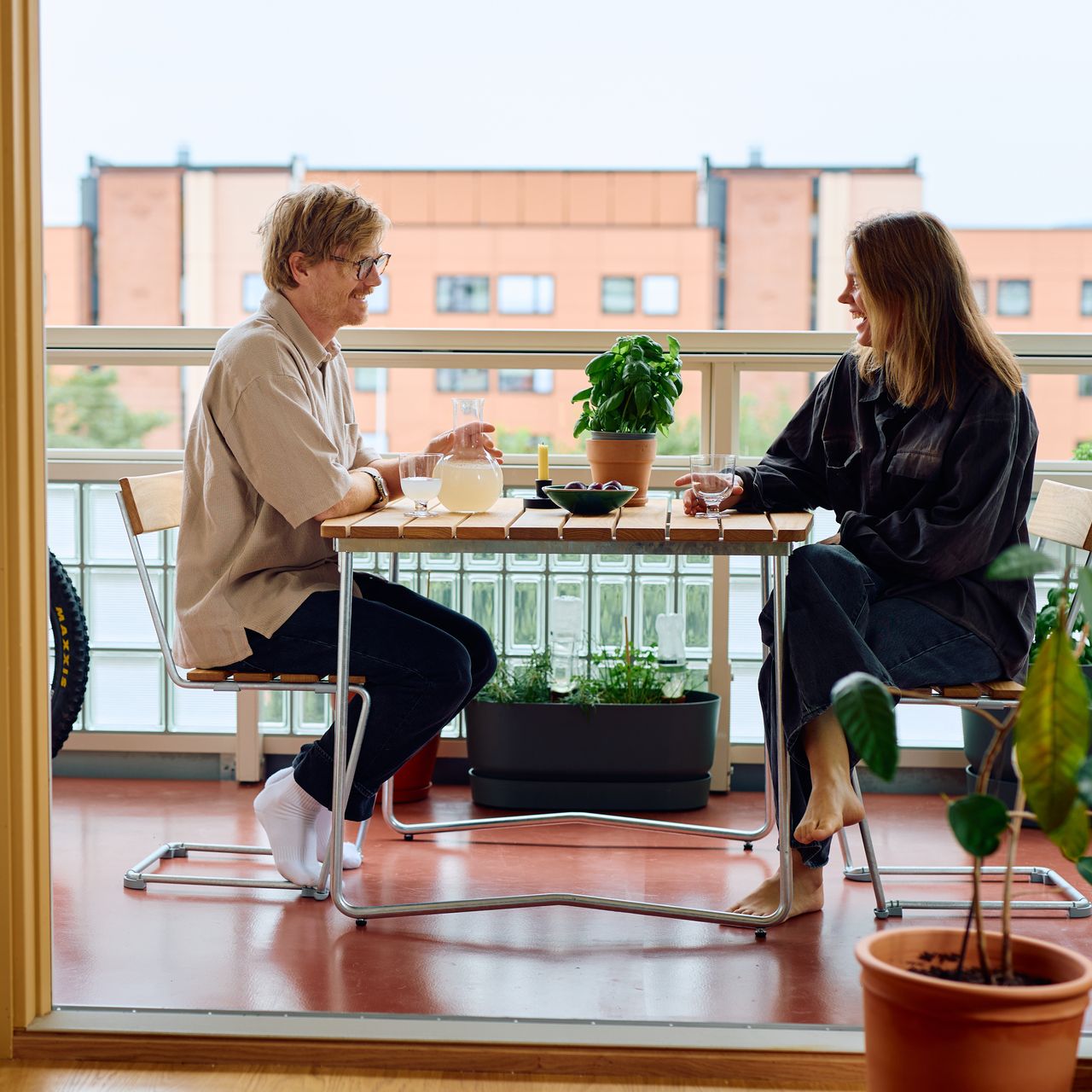 Foto av et par som går på en gangvei foran et leilighetskompleks. På hver side av gangveien er det strå og trær.