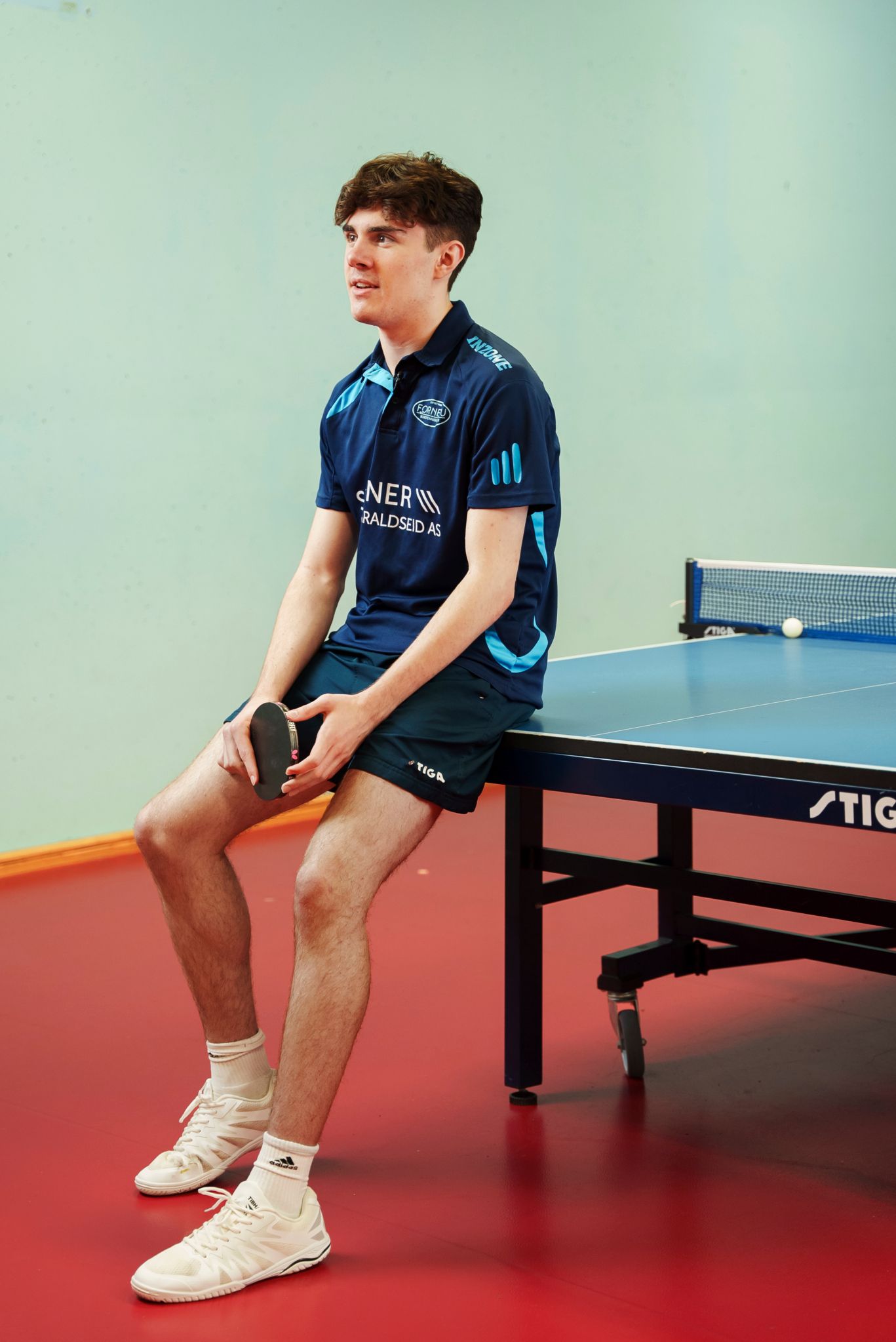 Michael lener seg mot bordtennisbordet.