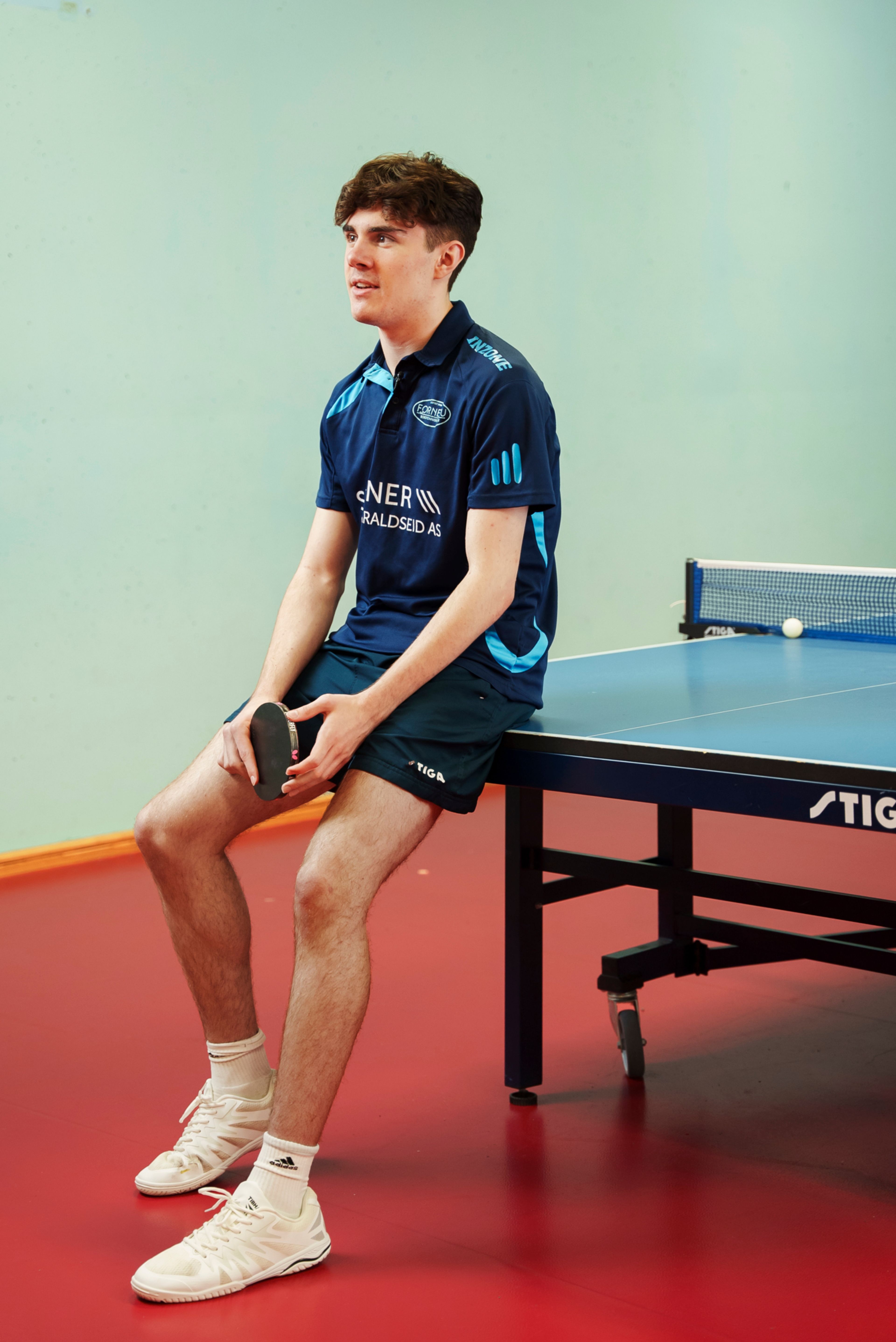 Michael lener seg mot bordtennisbordet.