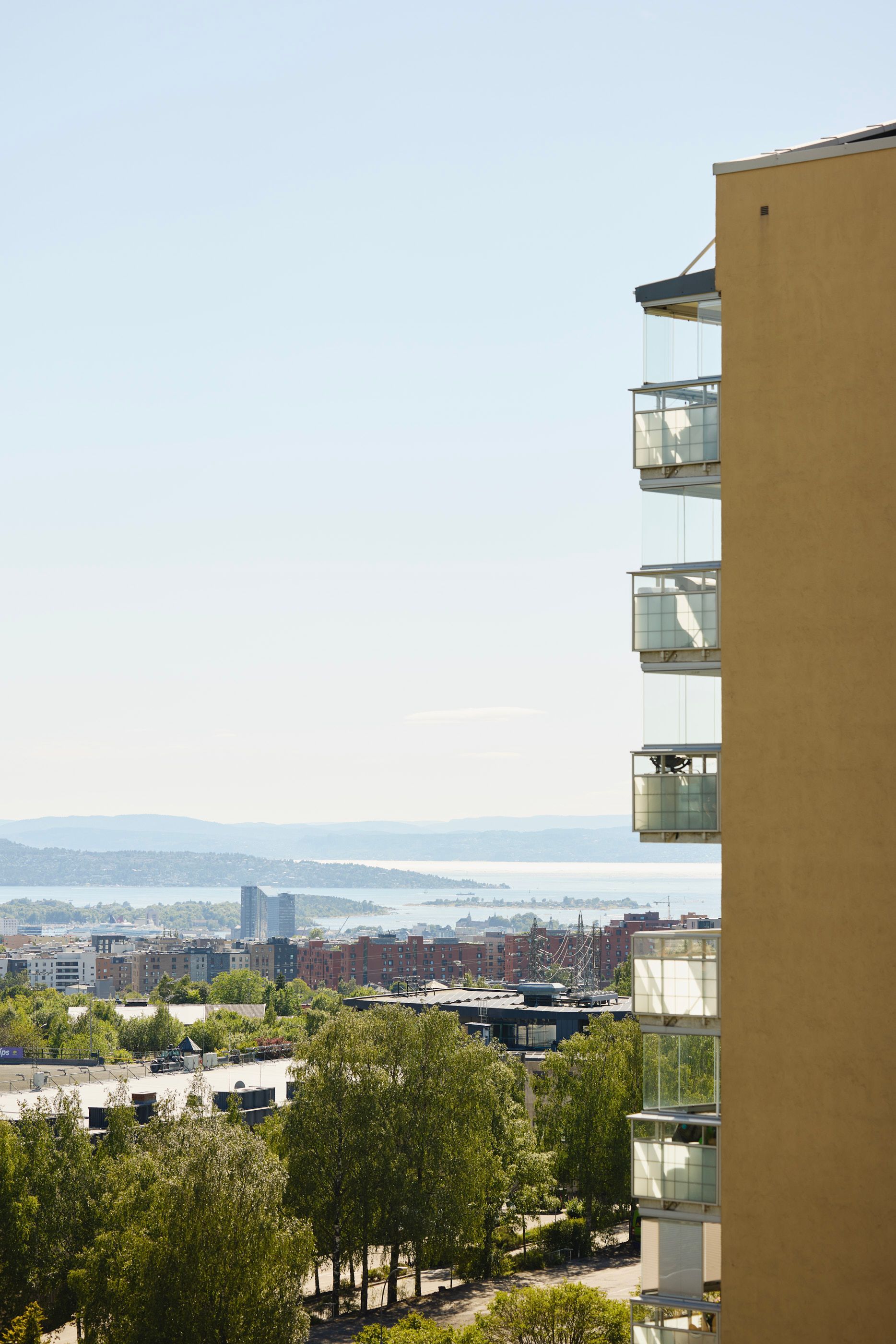 Høyt boligbygg med balkonger og utsikt over Oslo by og fjorden en solrik dag