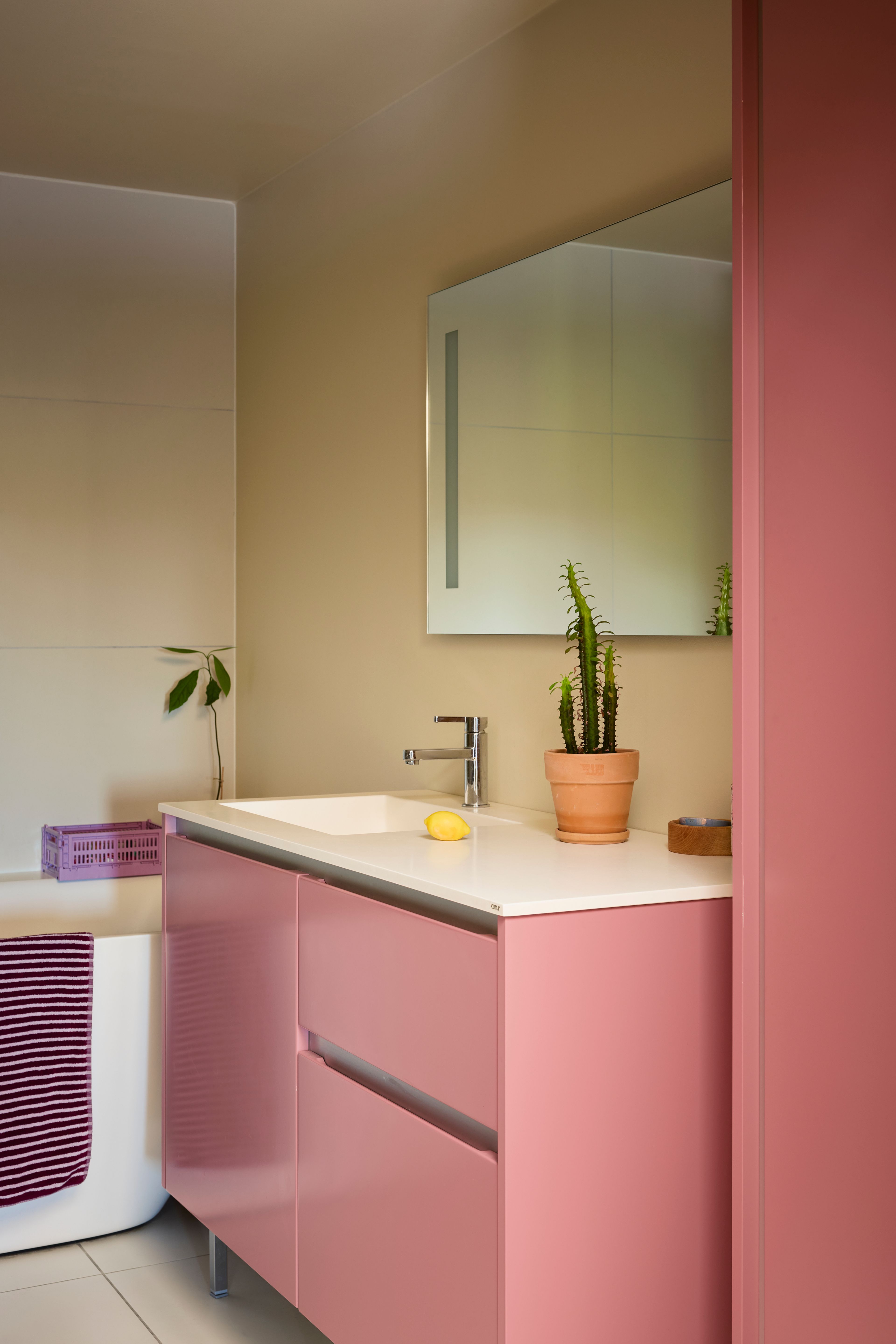 Bad med badekar og et varmrosa innredning. 