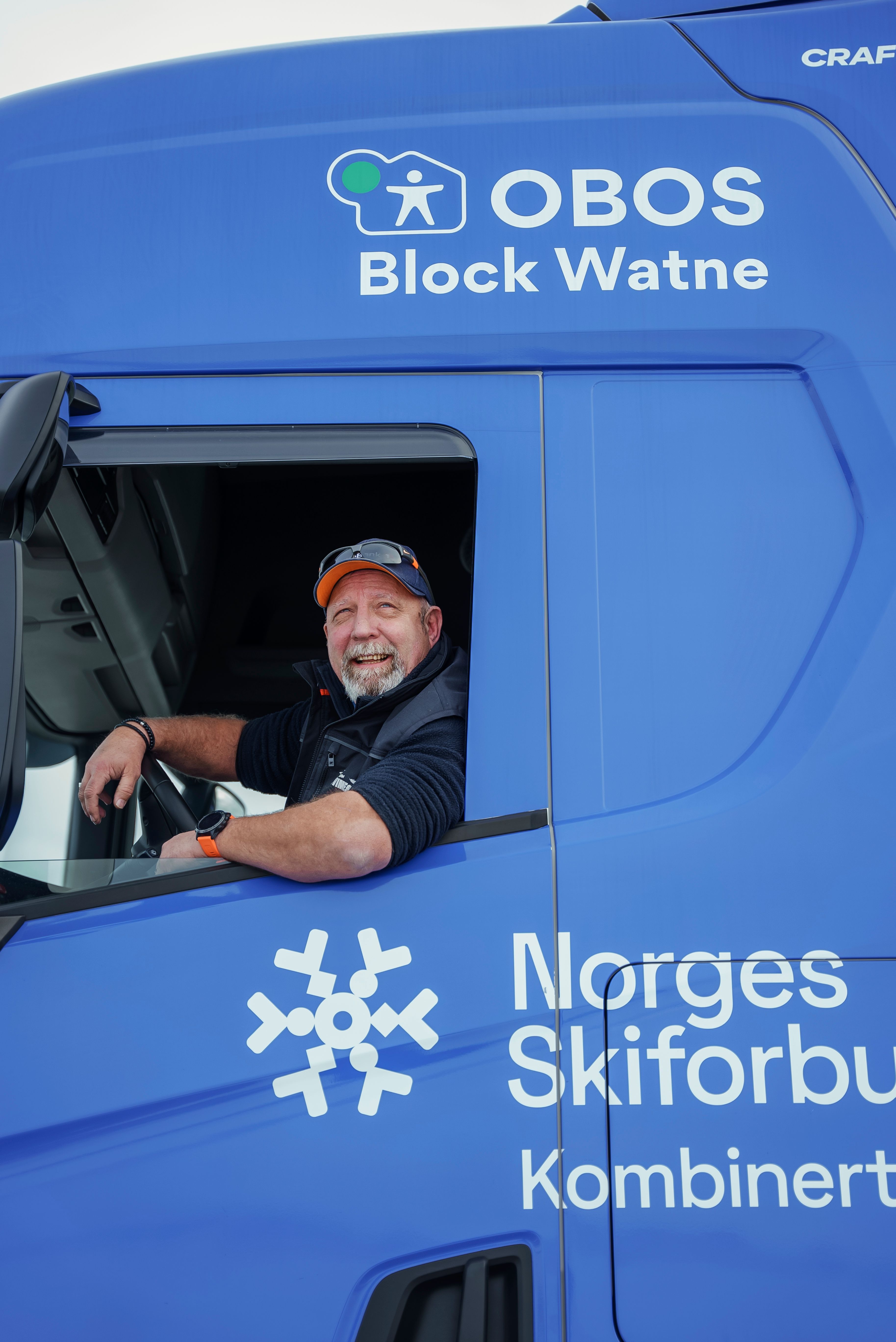 Henrik Algerheim ser smilende ut av førerhuset sitt i smøretraileren.