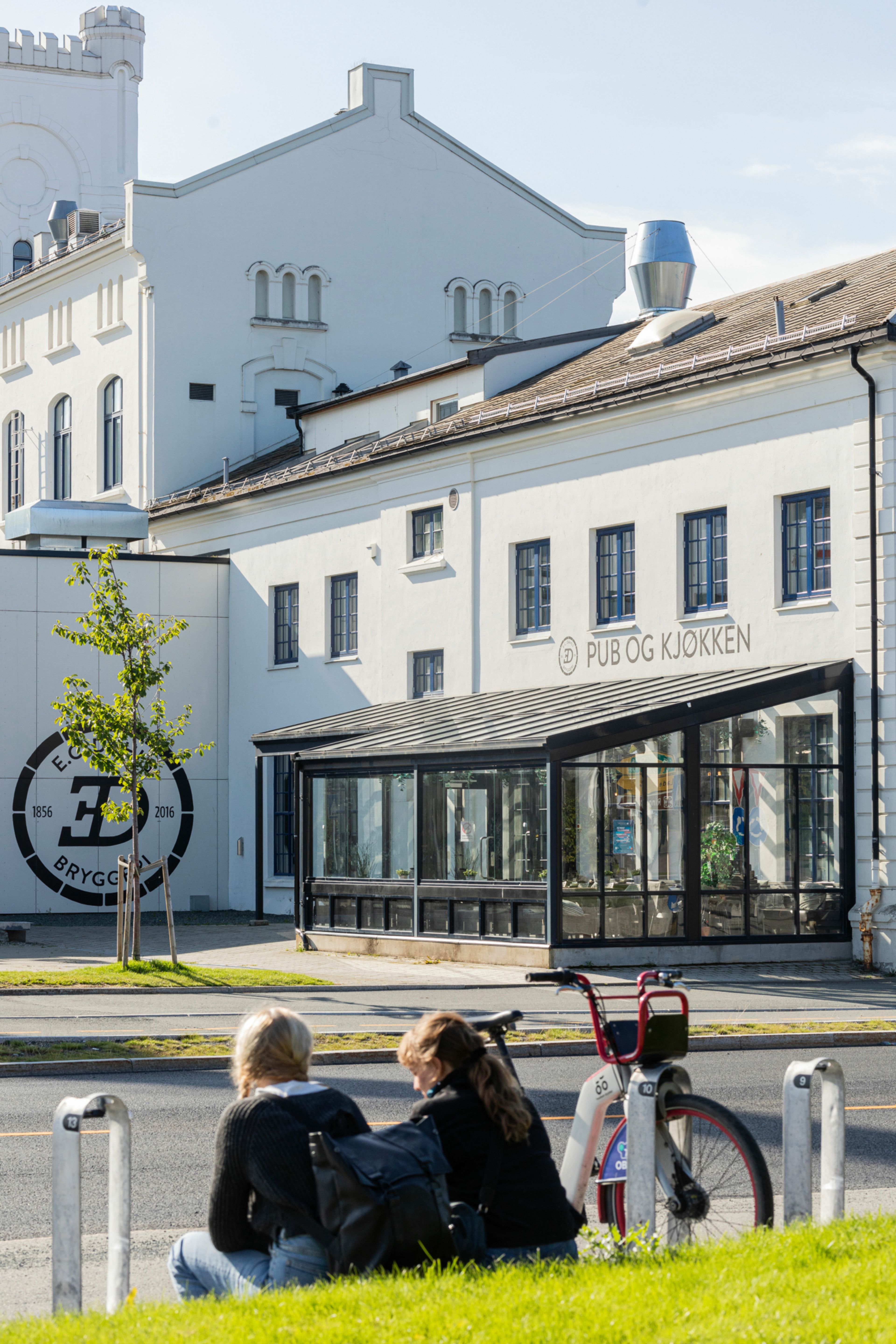 To mennesker som sitter foran restauranten Pub og Kjøkken på Jarlheim.