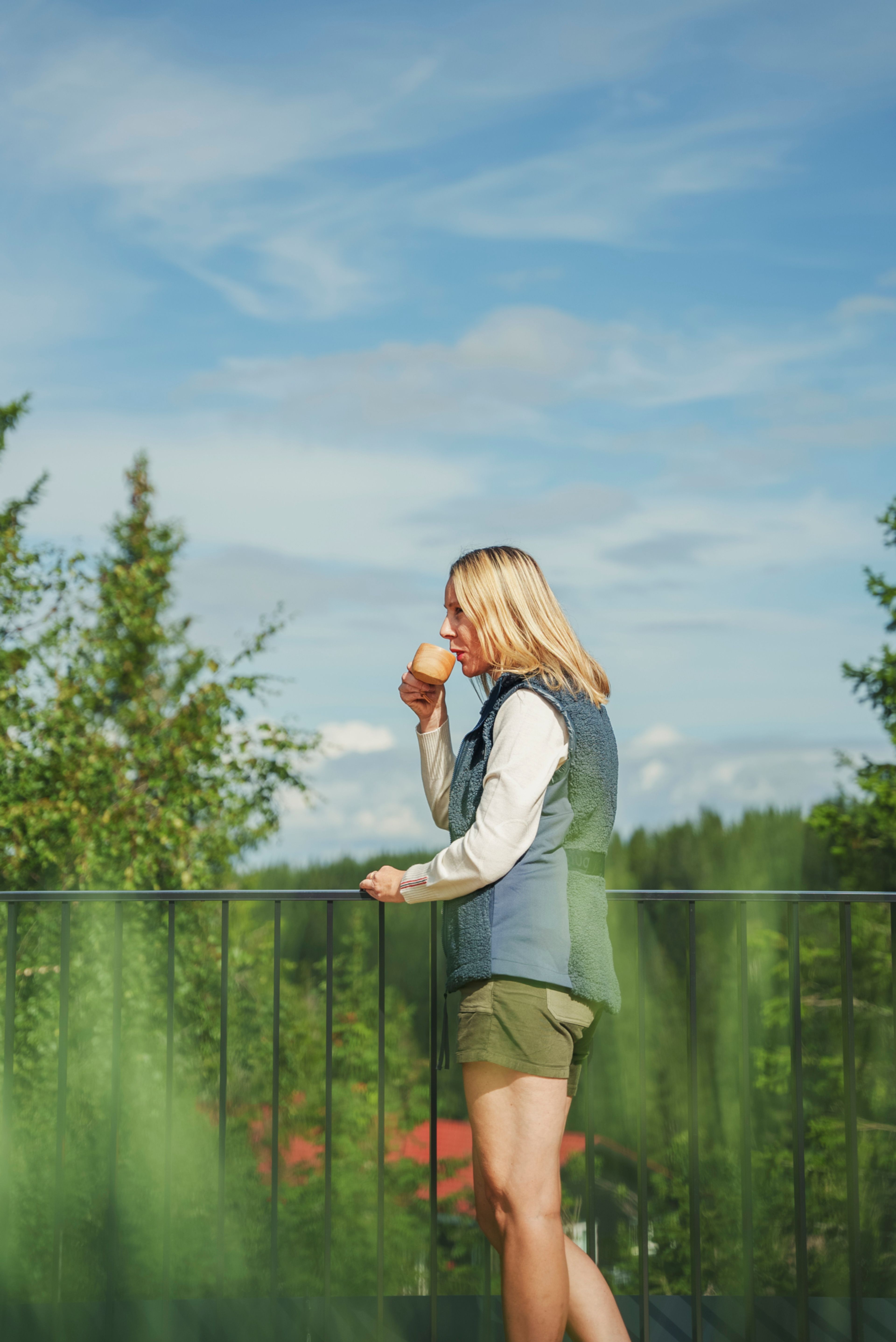 Nina Kindt ute på en takterrasse med utsikt ut over skog og grønne tretopper i Vitigrend