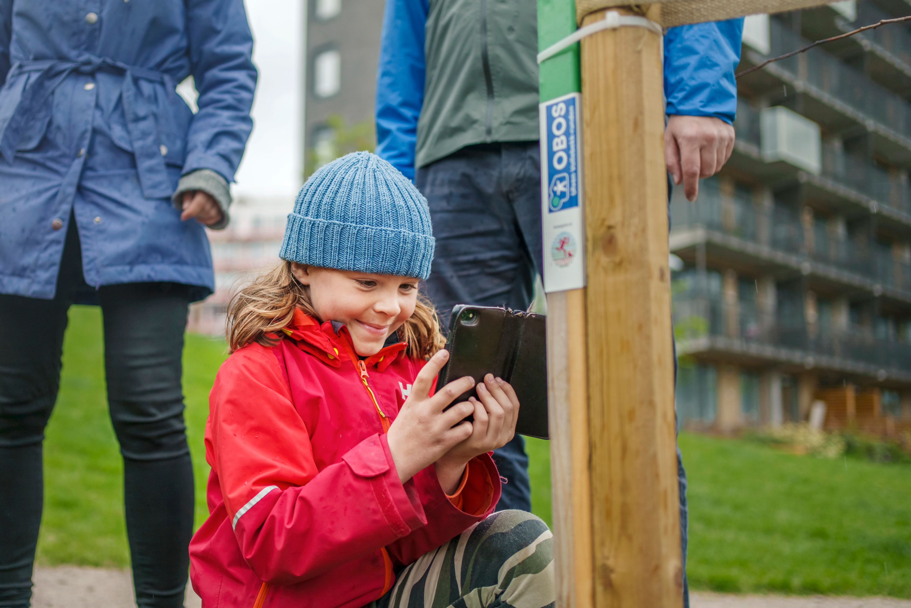 Familien Fredheim på stolpejakt på Ulven, hvor det ene barnet scanner en stolpe med mobilen.