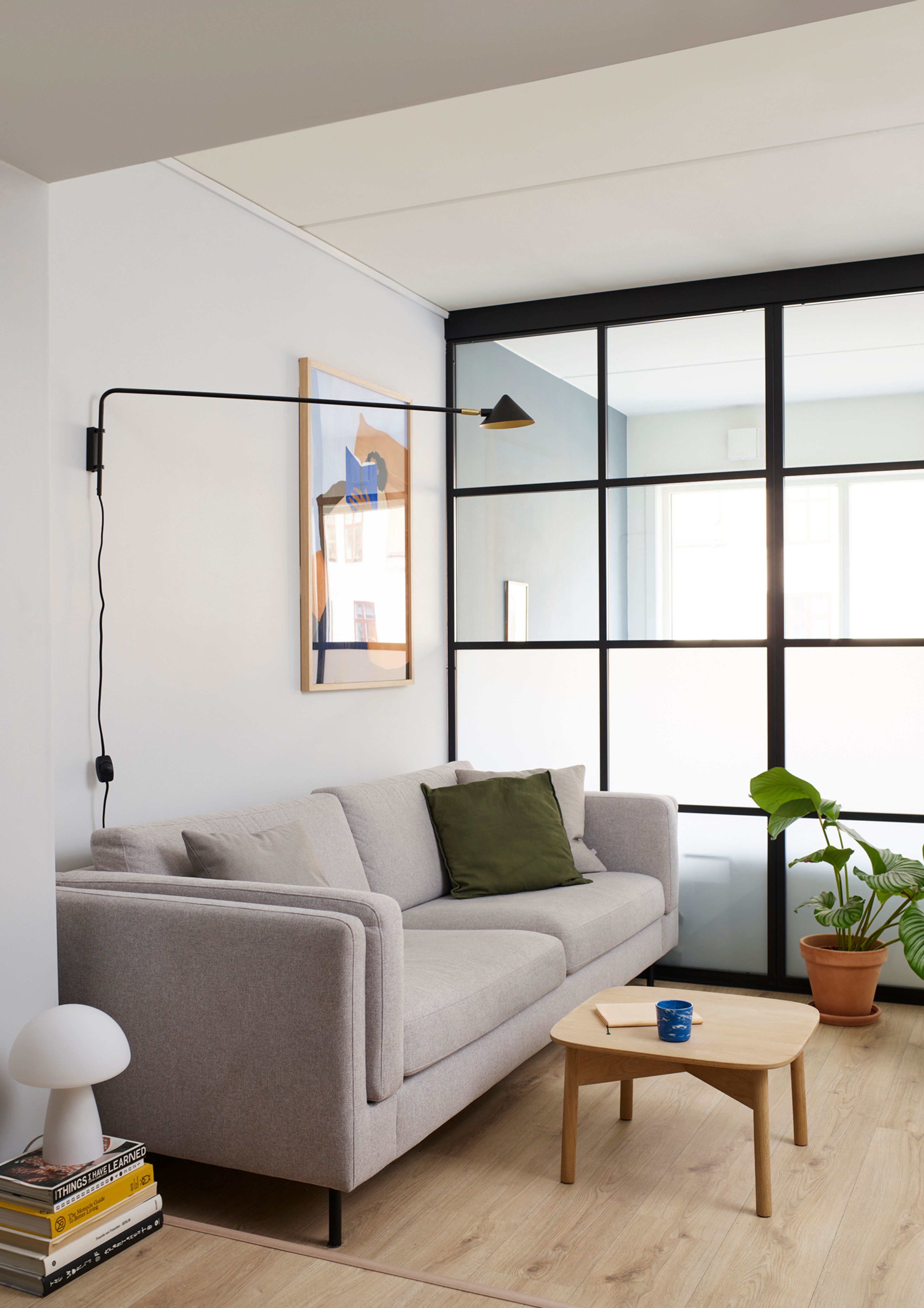 Sofahjørne med grå sofa fra Maxbo, leselampe og bord. Lyst gulv fra Maxbo.