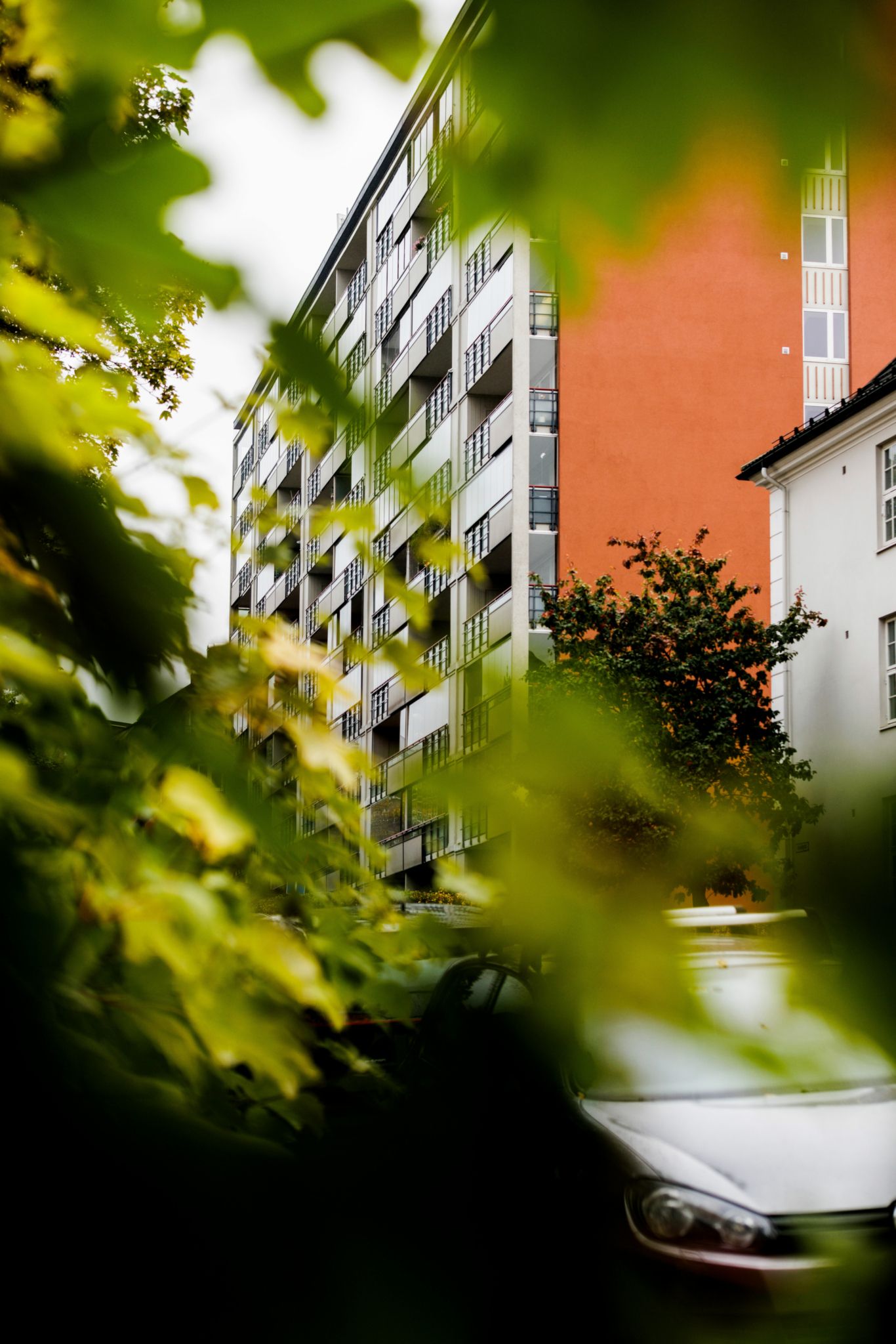 Bilde av den oransje fasaden på Dynekilgata 15 borettslag, tatt gjennom en busk