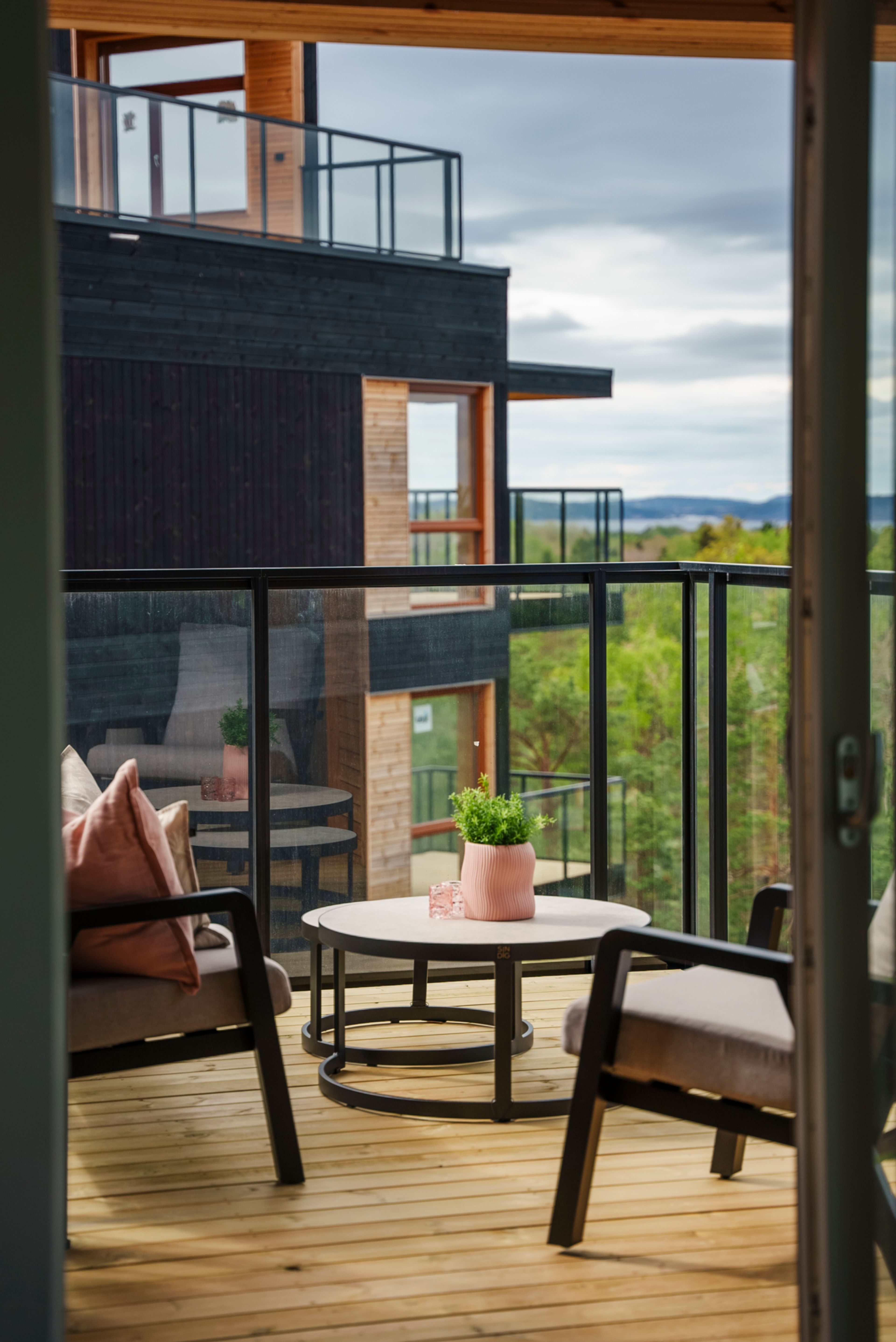 Innredet balkong i Furukrona med grønn utsikt og rosa pynte detaljer.