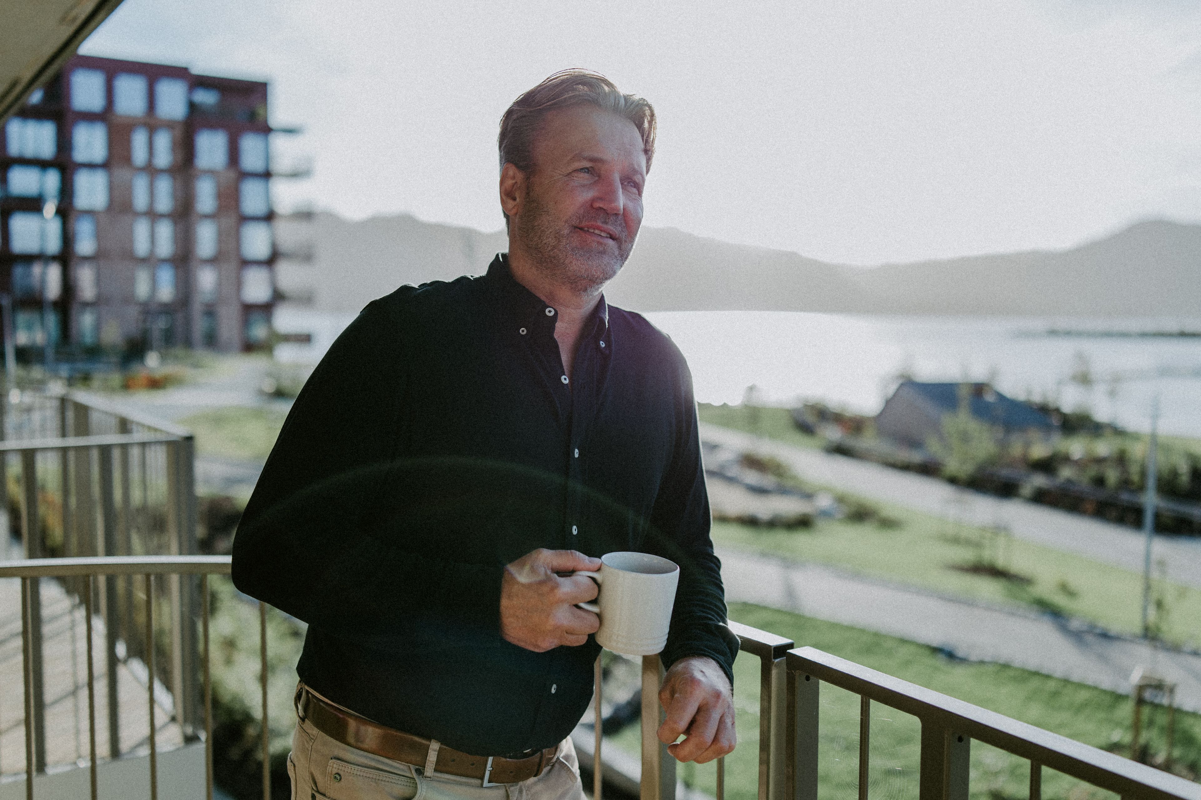 Even Aase nyter utsikten fra balkongen på Odden med en kaffekopp i hånda