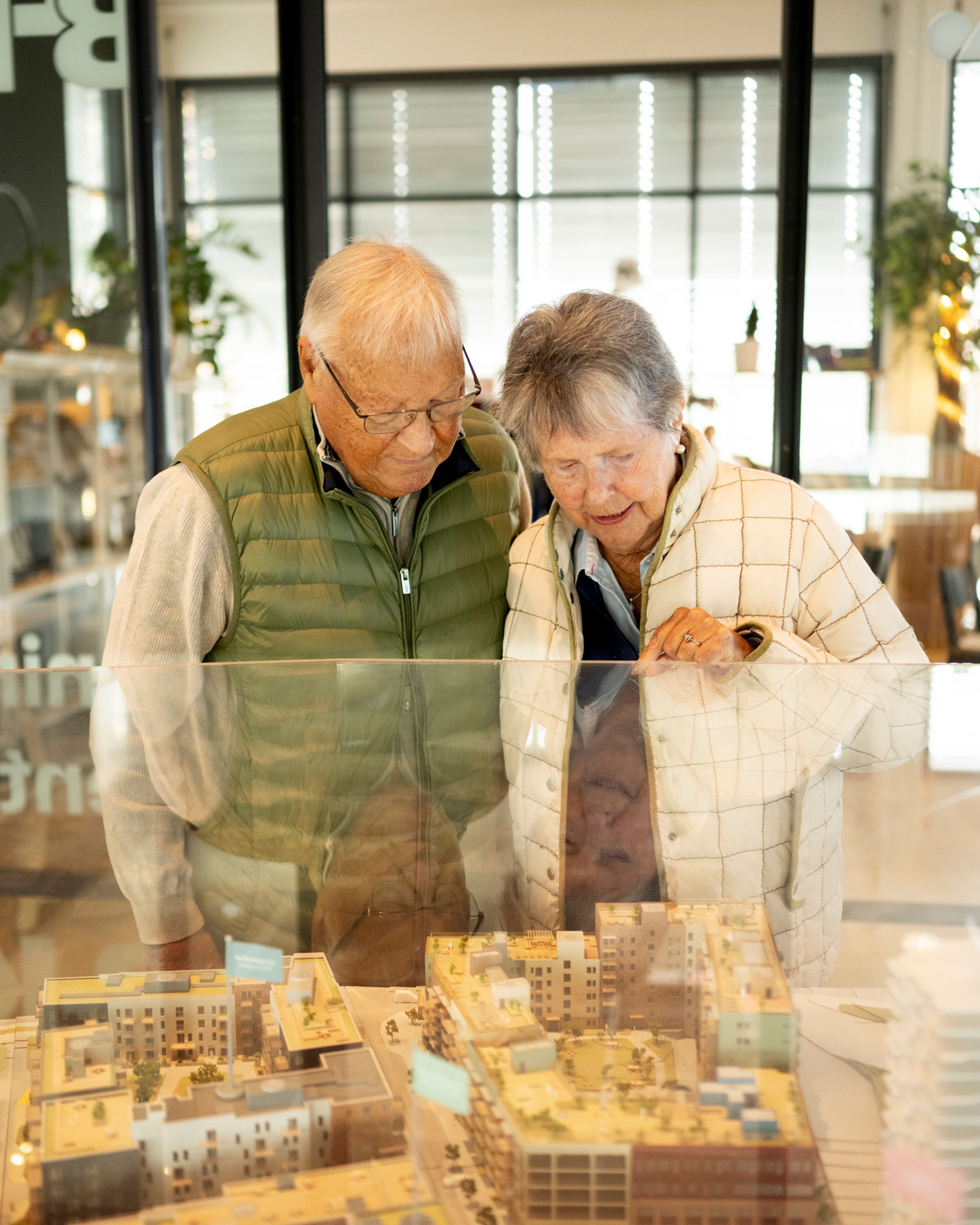 Foto av beboerne Clas og Lise som ser på 3D-modell av utbyggingen av Vollebekk Torgkvartal.