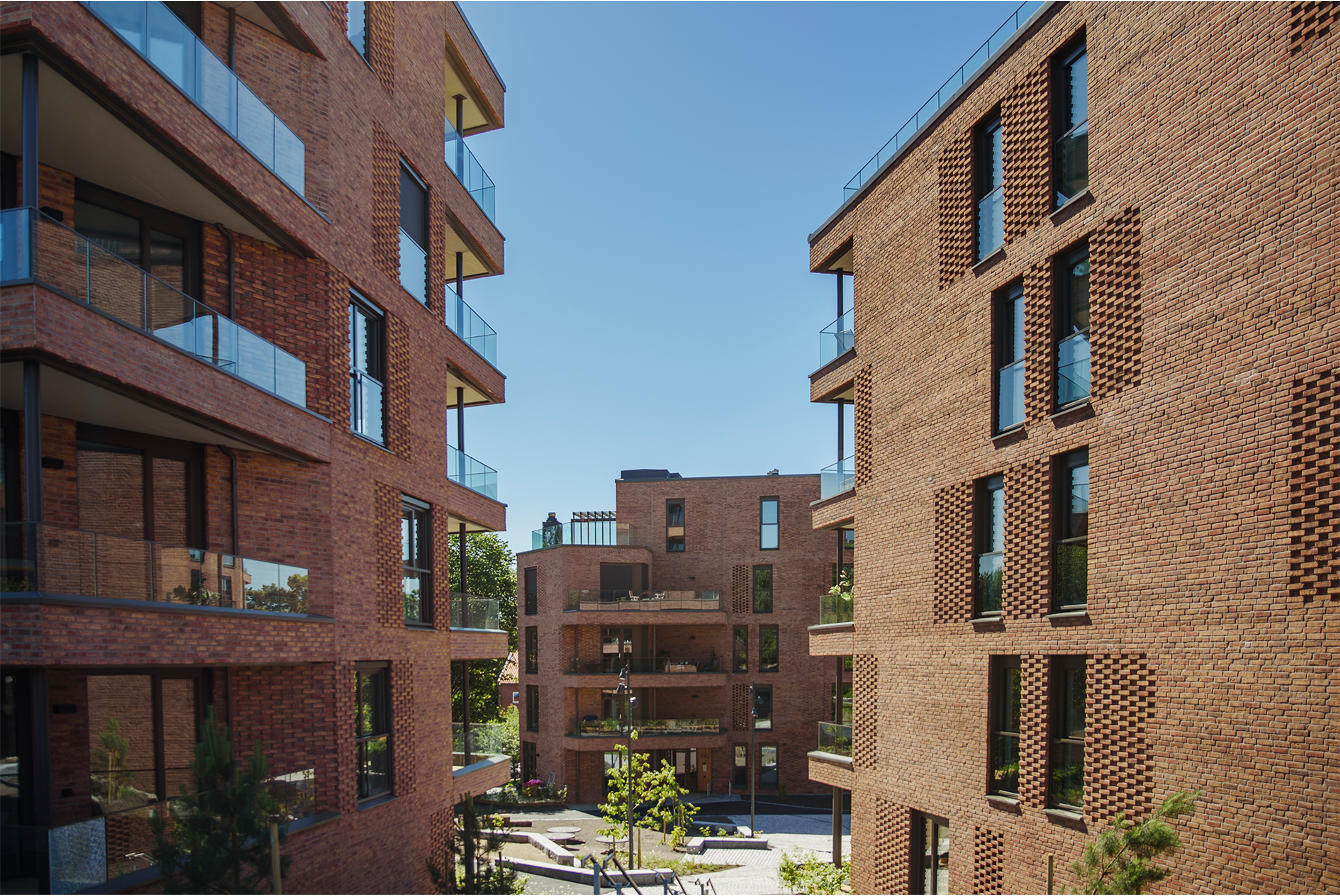 Et oversiktsbilde utover fellesområdet på Hoffsveien Hage, omgitt av de brune, moderne mursteinsblokkene