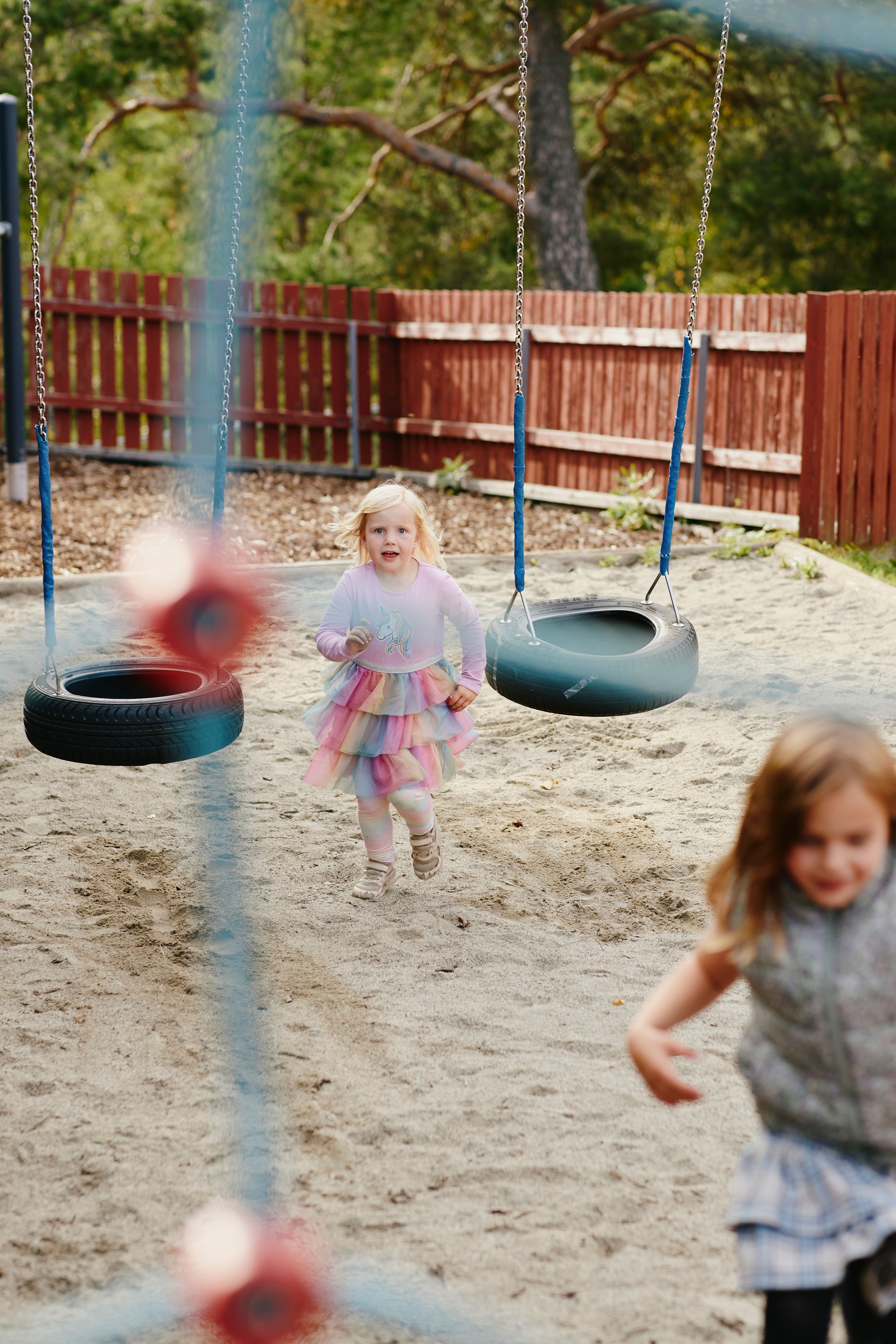 Søstrene løper rundt på lekeplassen.