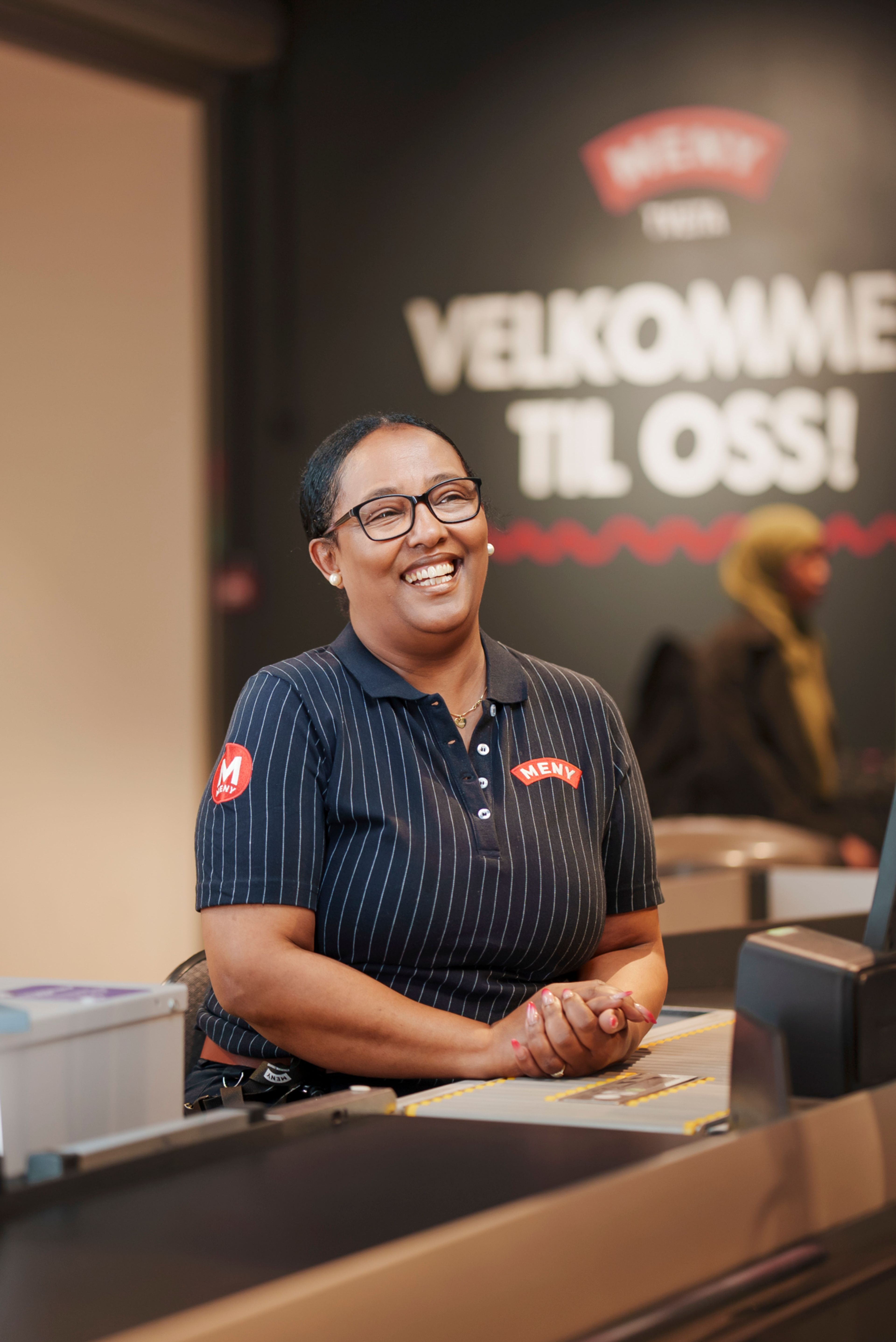 Senait sitter ved kassa på Meny på Tveita Senter.