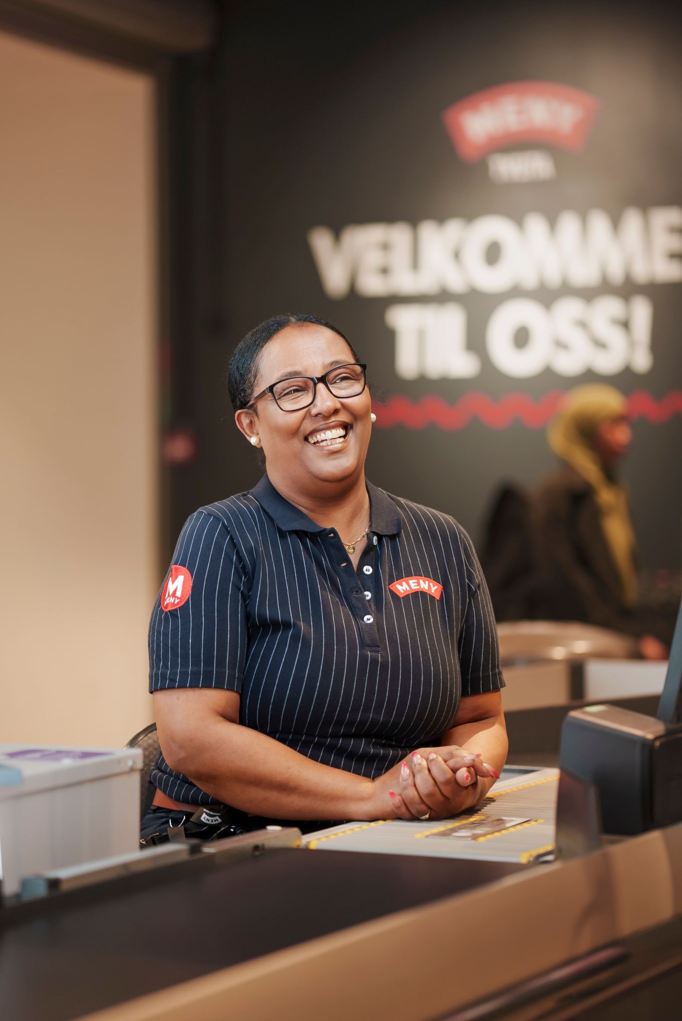 Senait sitter ved kassa på Meny på Tveita Senter.