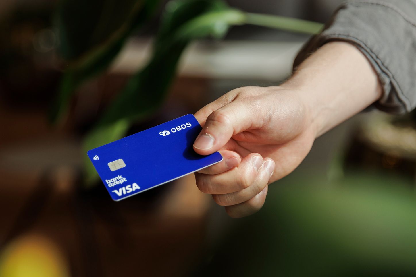 En hånd strekker frem et OBOS-bankkort
