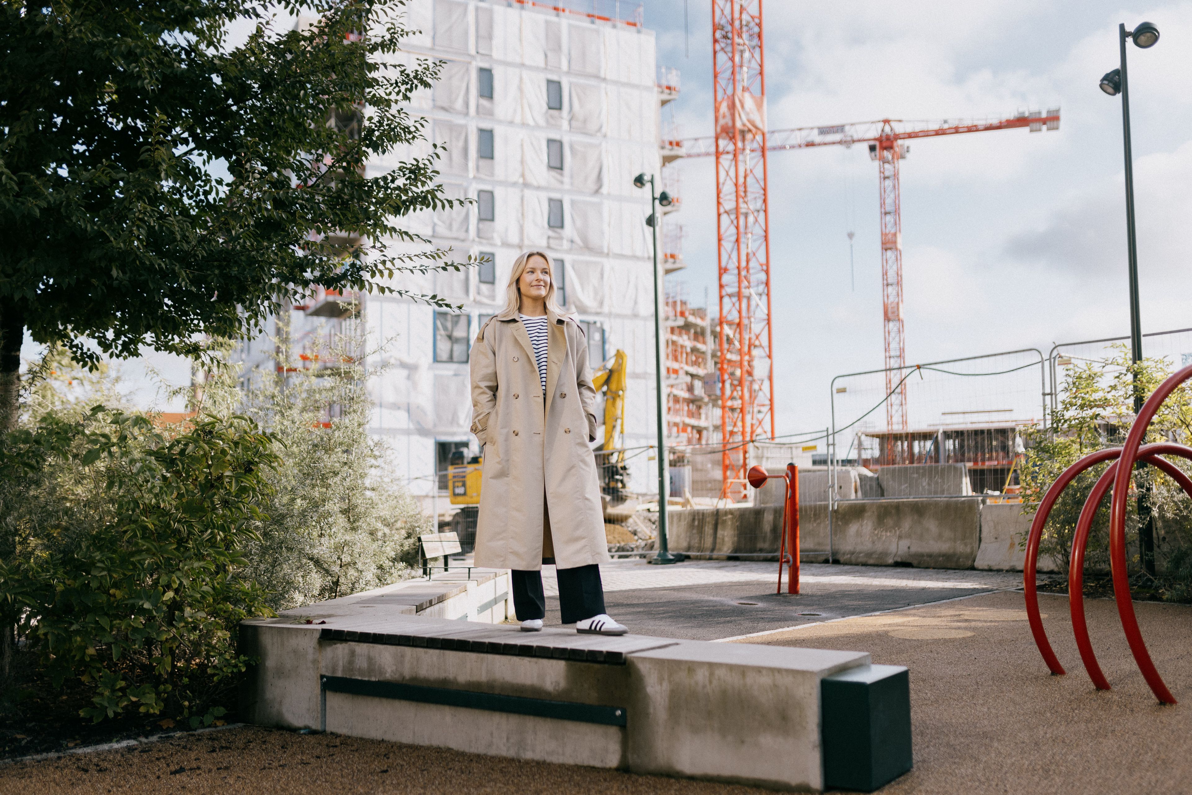 Foto av Brita som står foran byggeområdet på Ulven hvor hun har kjøpt seg leilighet