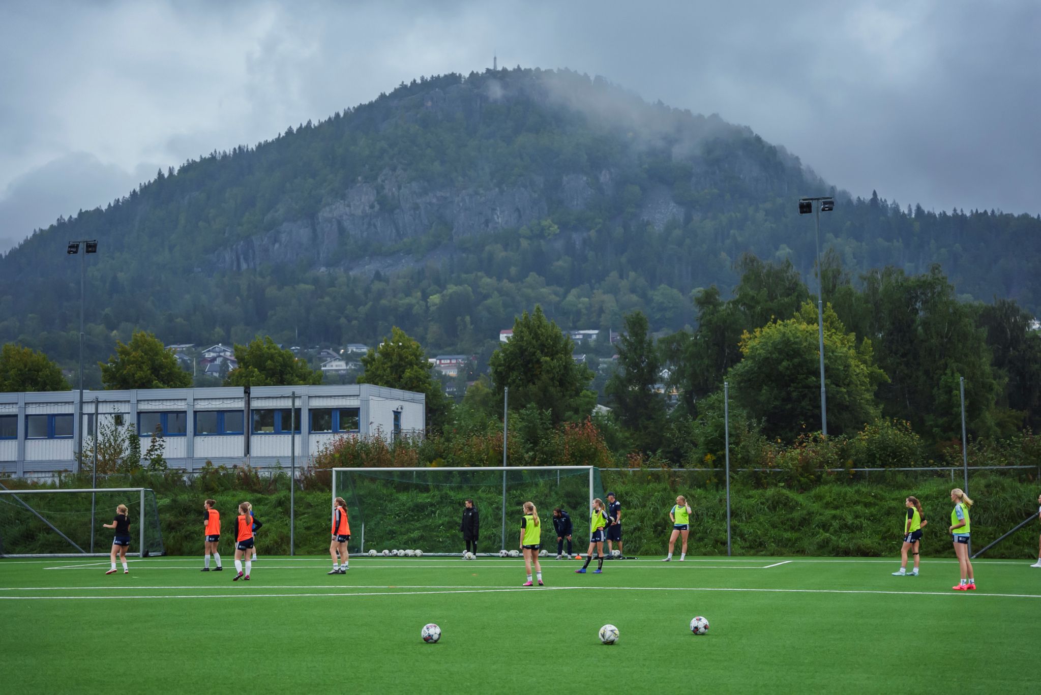 Et bilde underveis i treningen til jentene. Det er et oversiktsbilde fra avstand, som viser fjellet i bakgrunnen.