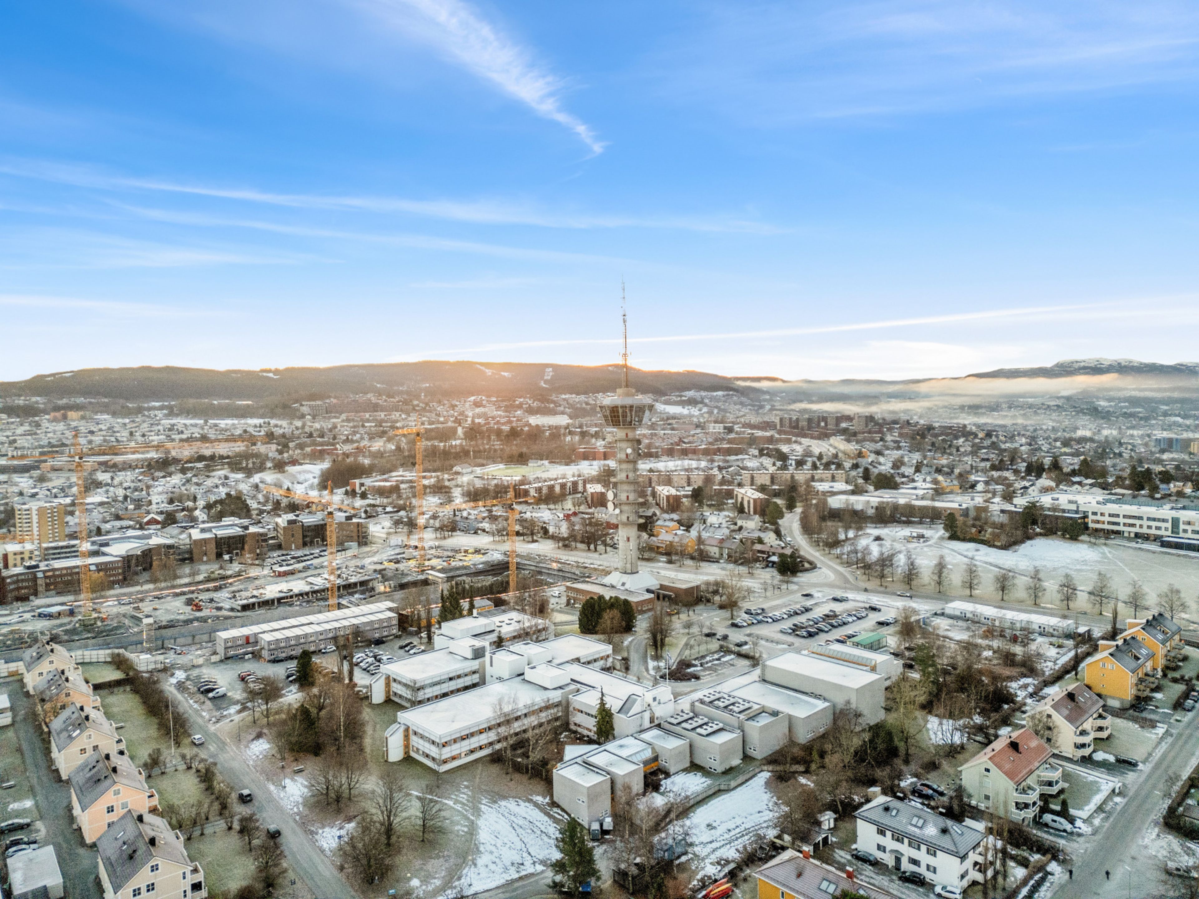 Oversiktsbilde over tomta med Tyholtårnet og Trondheim i bakgrunnen.
