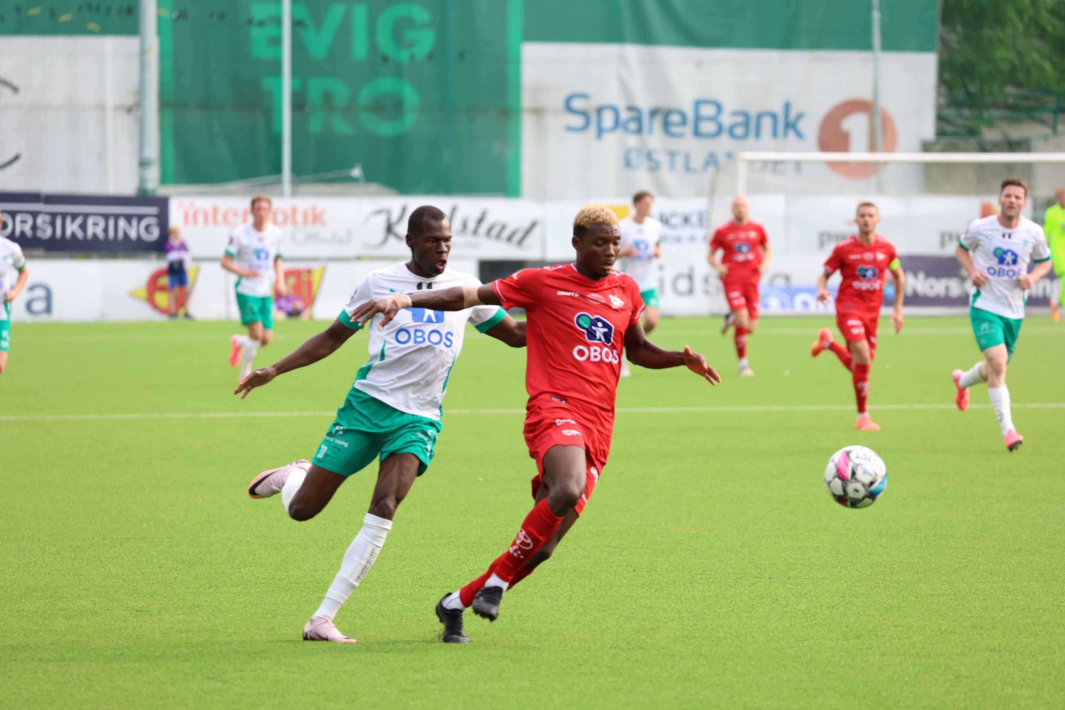 Foto av to fotballspillere som kjemper om ballen under fotballkampen.