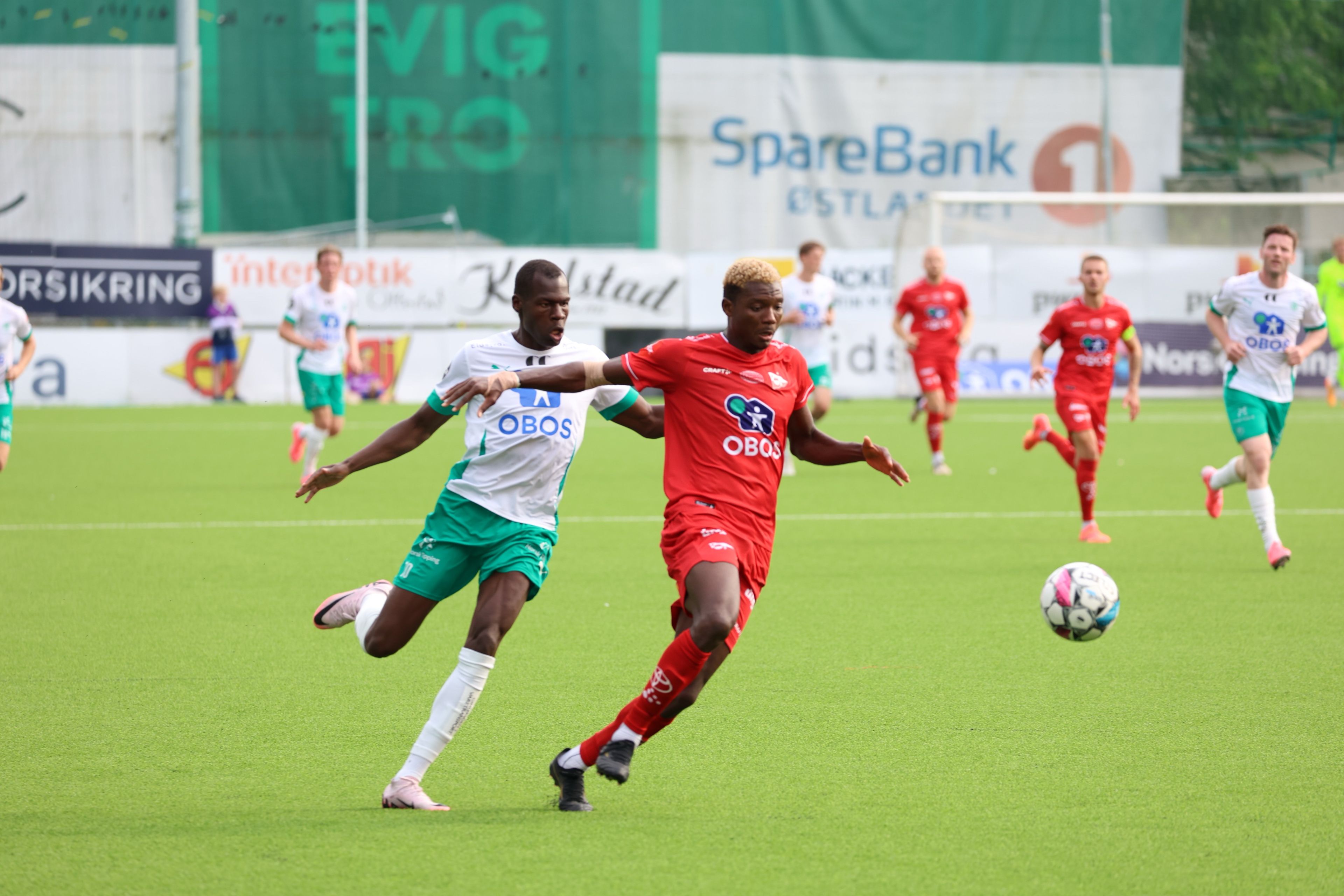Foto av to fotballspillere som kjemper om ballen under fotballkampen.