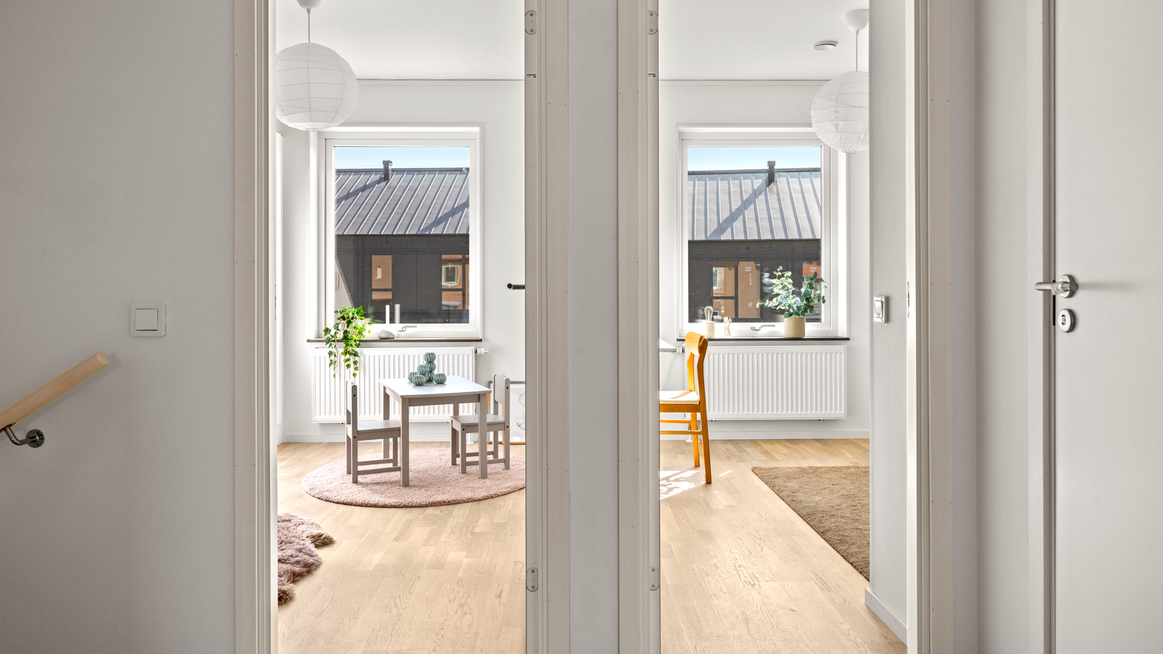 Bild med 2 dörröppningar och 2 fönster med utsikt mot mörka hus mitt emot