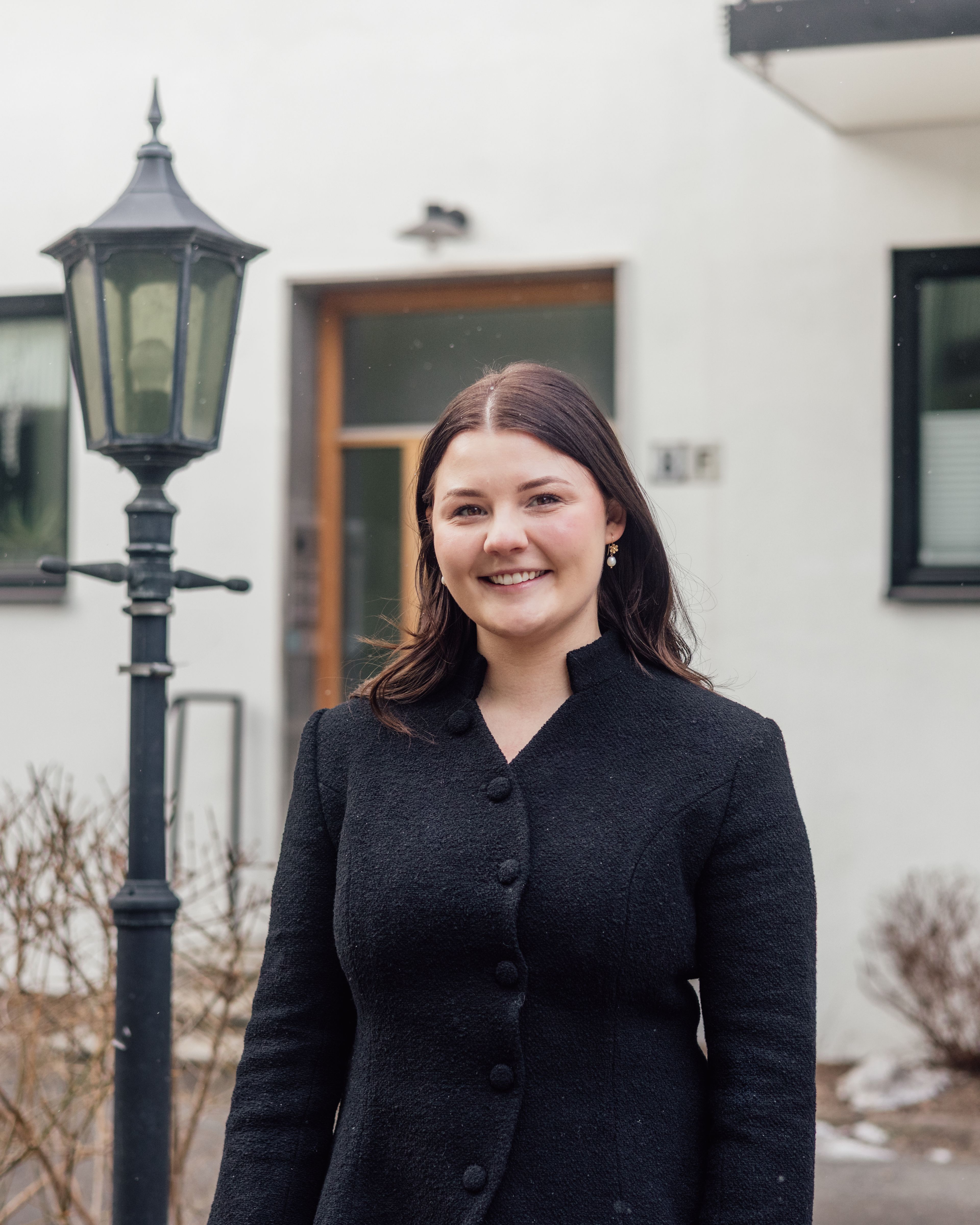 Nora Kristine står foran blokka hun bor i.