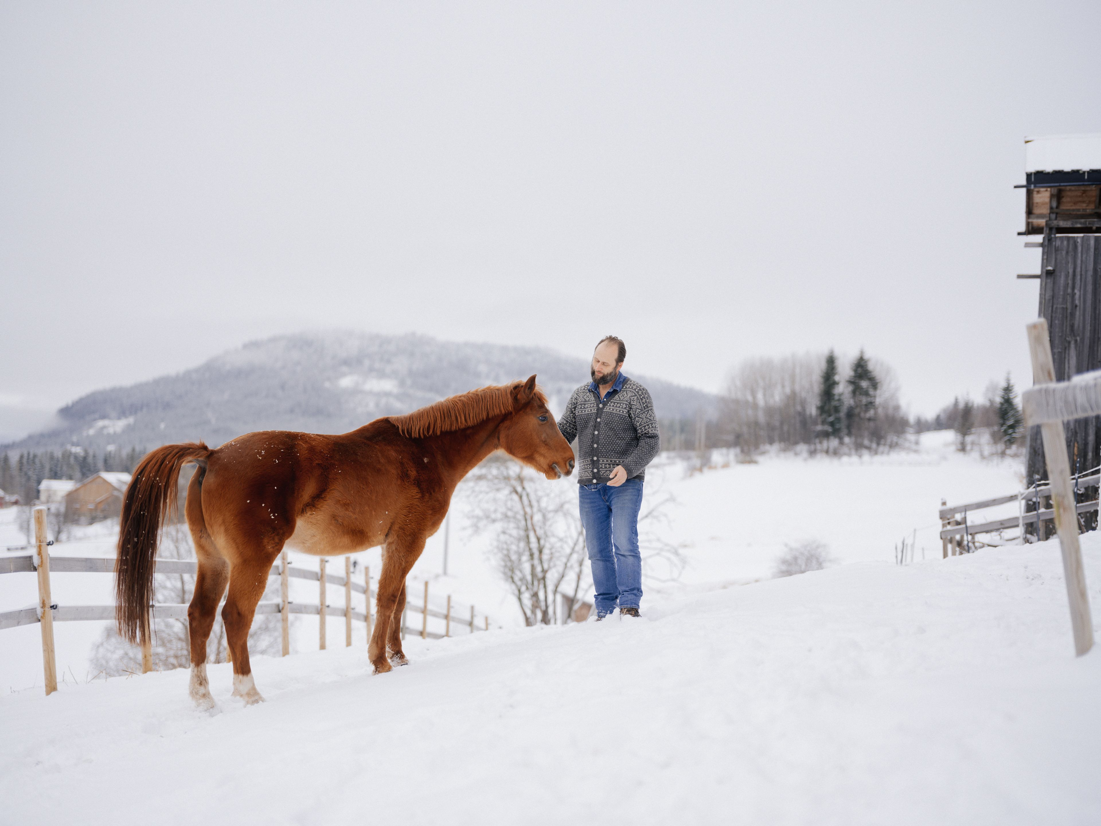 Bjella står på tunet i Ål og koser med en hest.