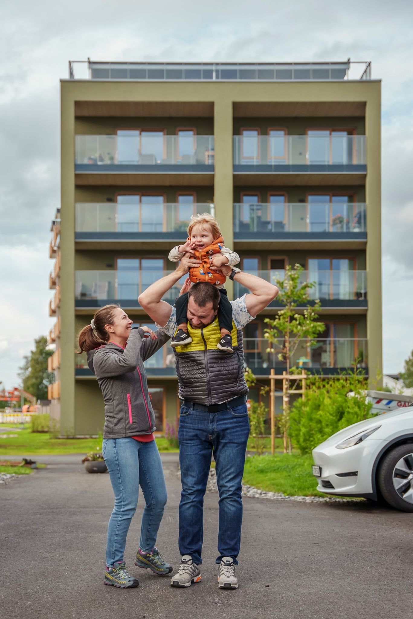 Maja og Nikola står foran en av blokkene i Asper Hageby med lille sønnen på skuldrene til Nikola