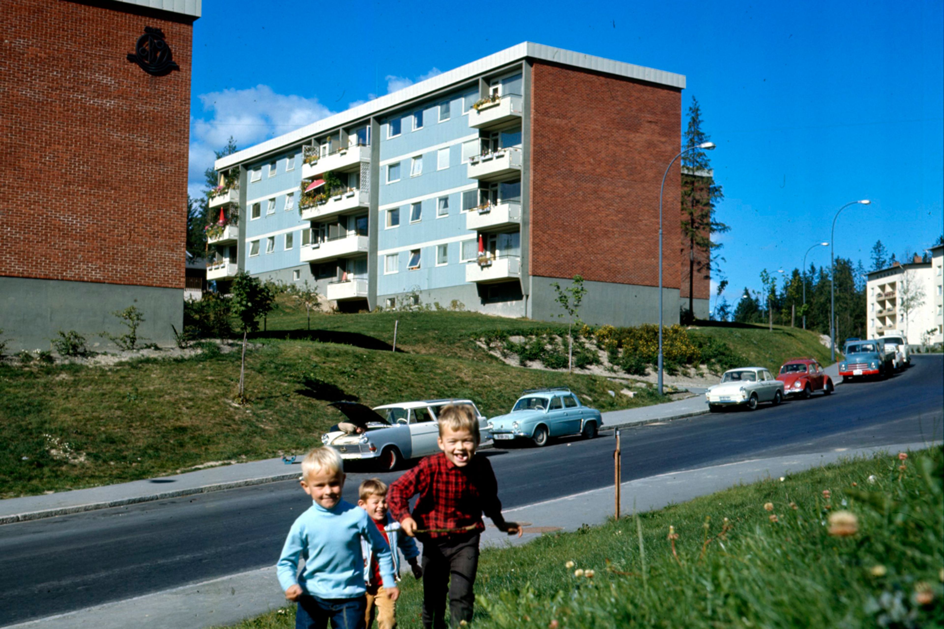 Arkivfoto fra Lambertseter med barn som løper i gresset foran noen blokker.