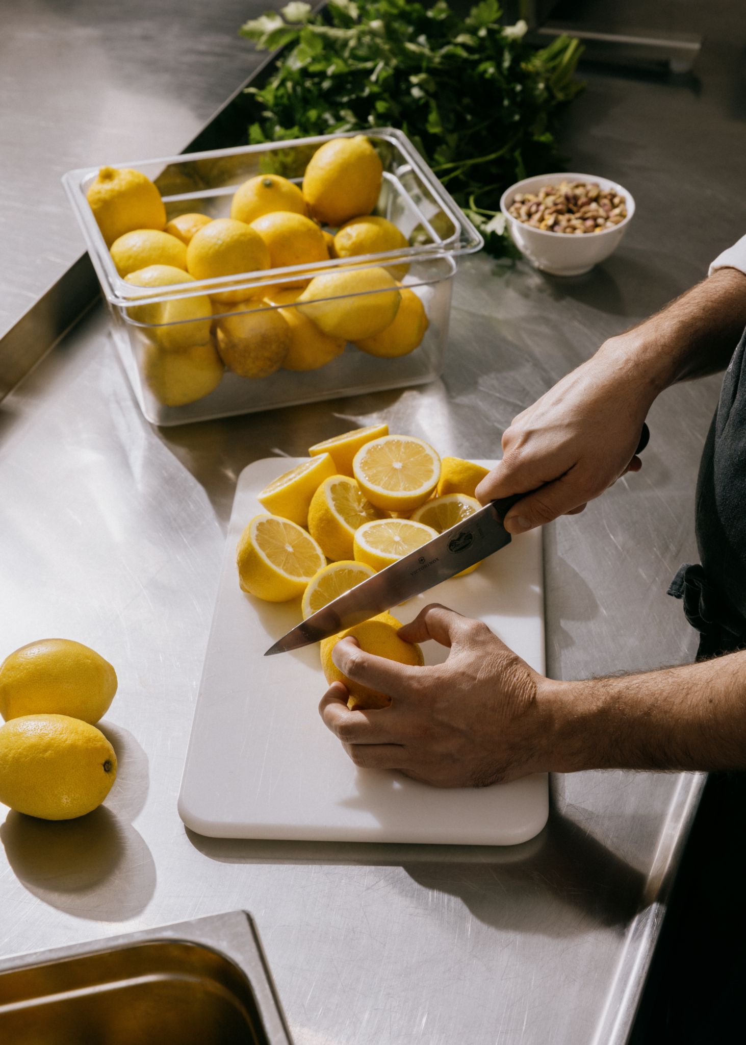 Bildet viser hender som skjærer opp en stor haug med sitroner.