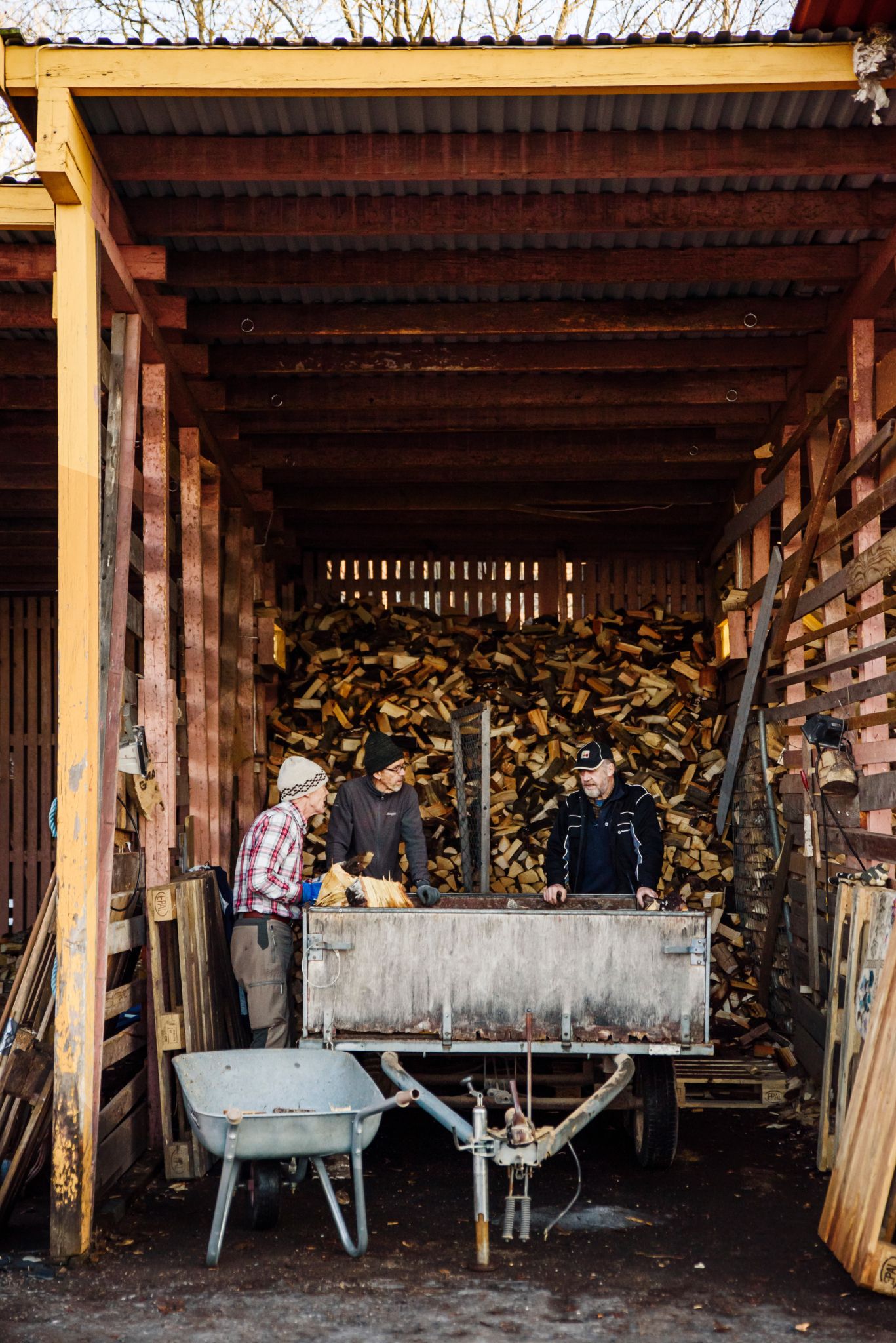 Frivillige i Operasjon Ved snakker sammen ved en brakkerigg som er fylt opp med ved.