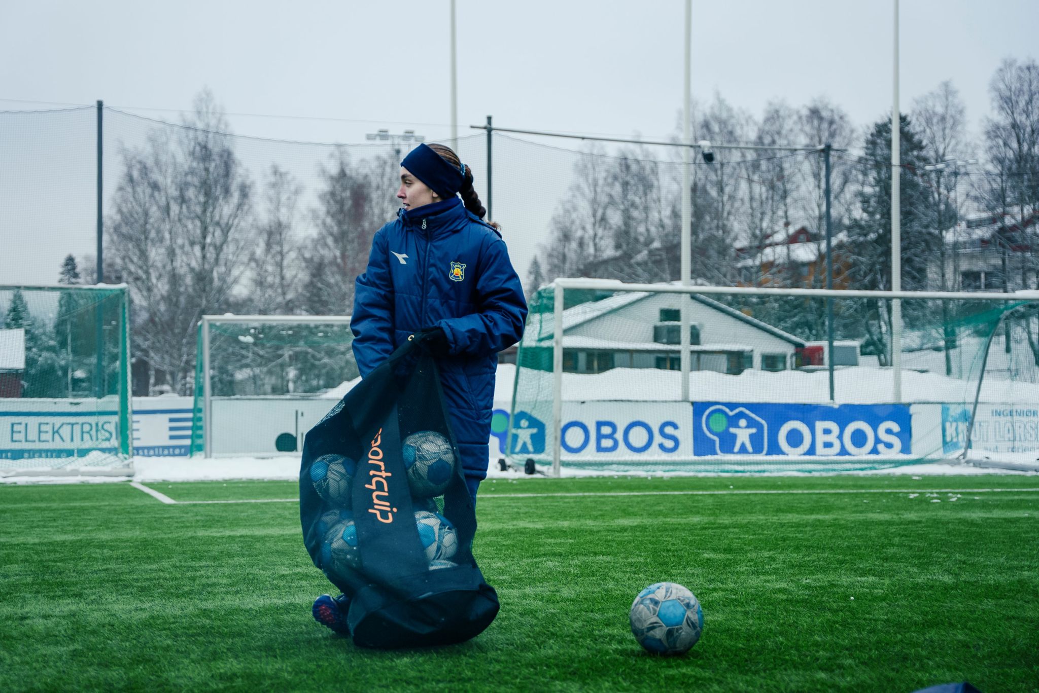 Bilde av Sara som rydder fotballer oppi ballnettet ute på banen.