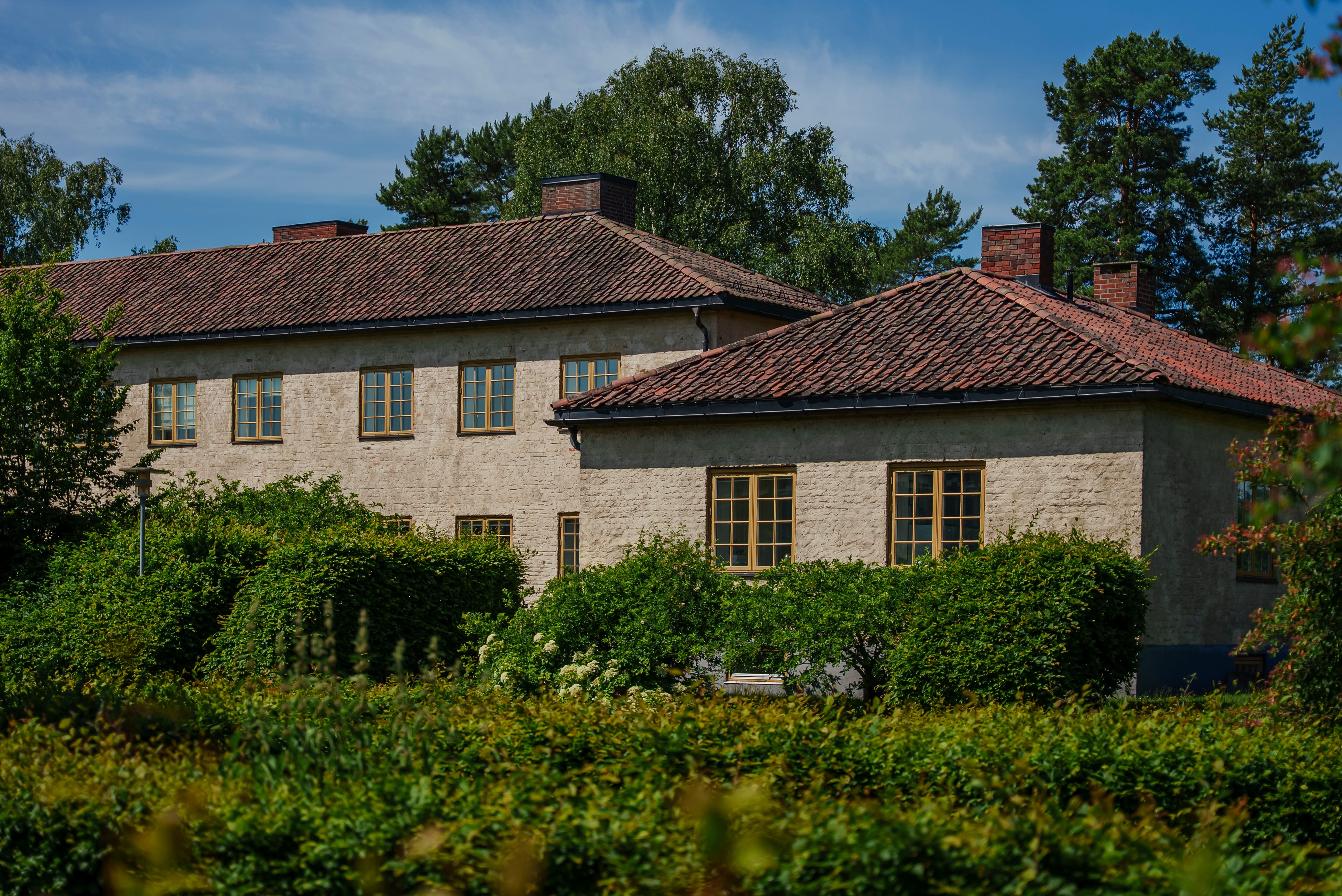 Gammelt murhus ved Oksenøya Bruk og grønn vegetasjon i forgrunnen