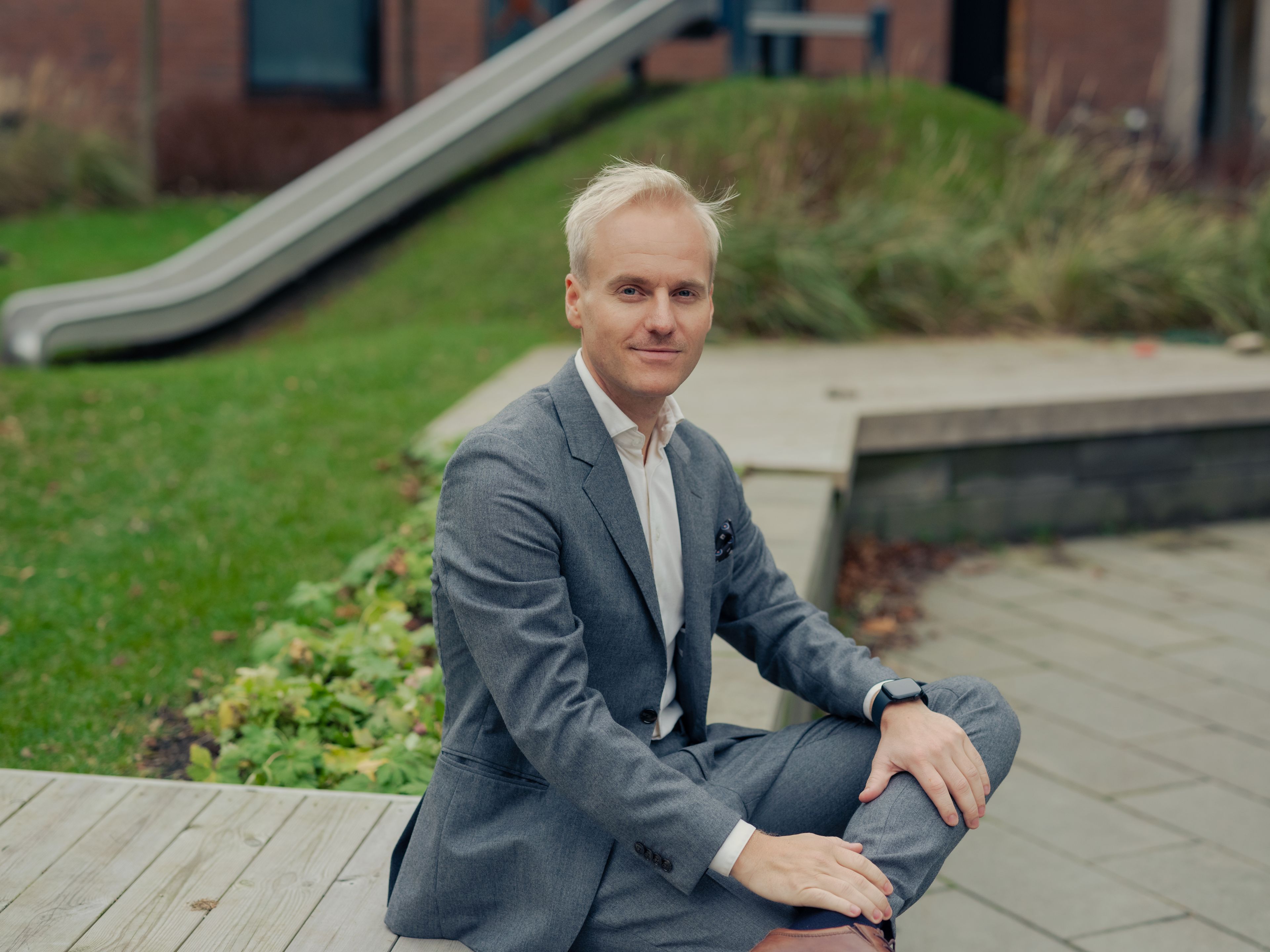 Niklas Røen Antonsen fra OBOS Eiendomsmeglere sitter på en benk.