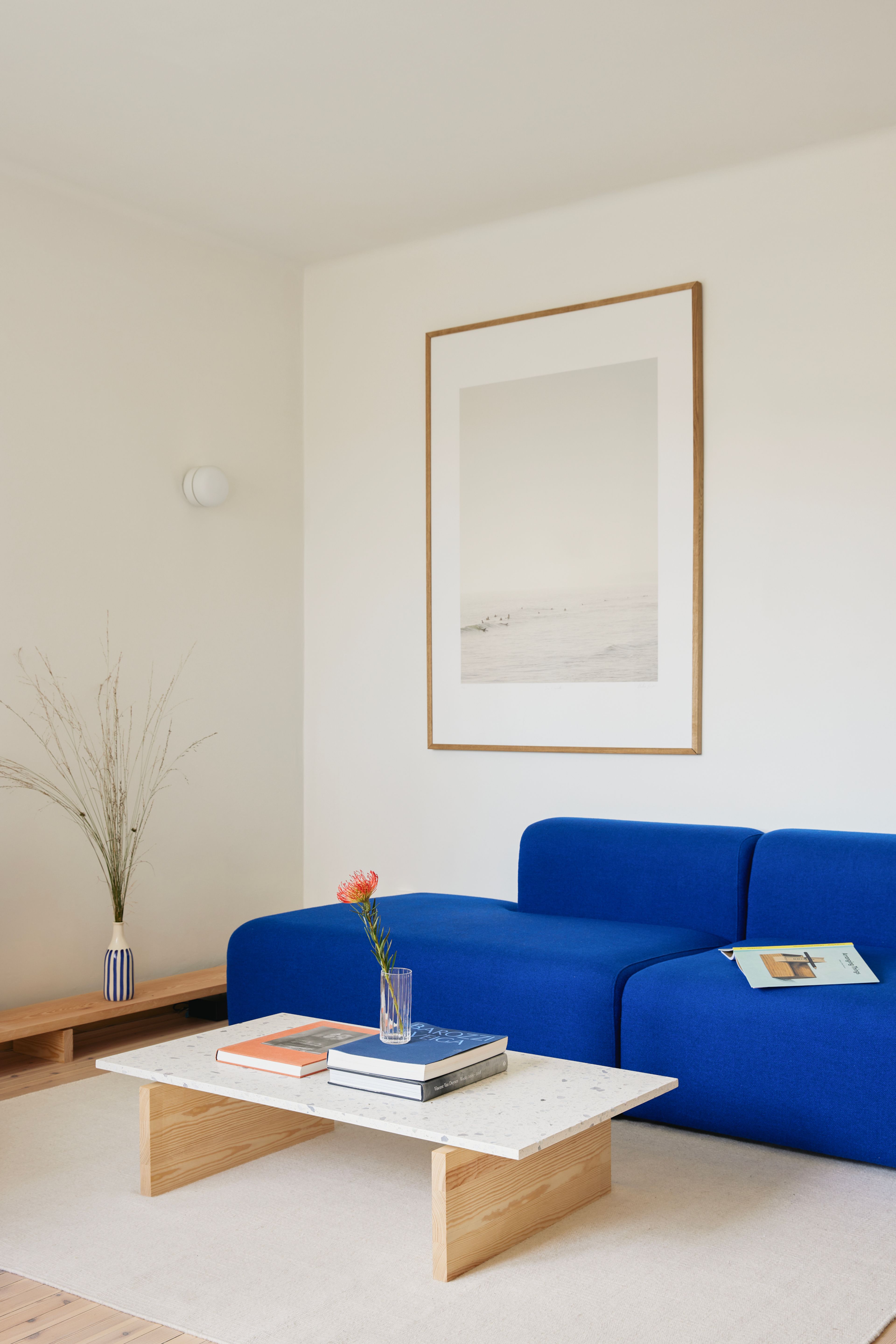 En blå sofa og et stuebord med marmorplate.