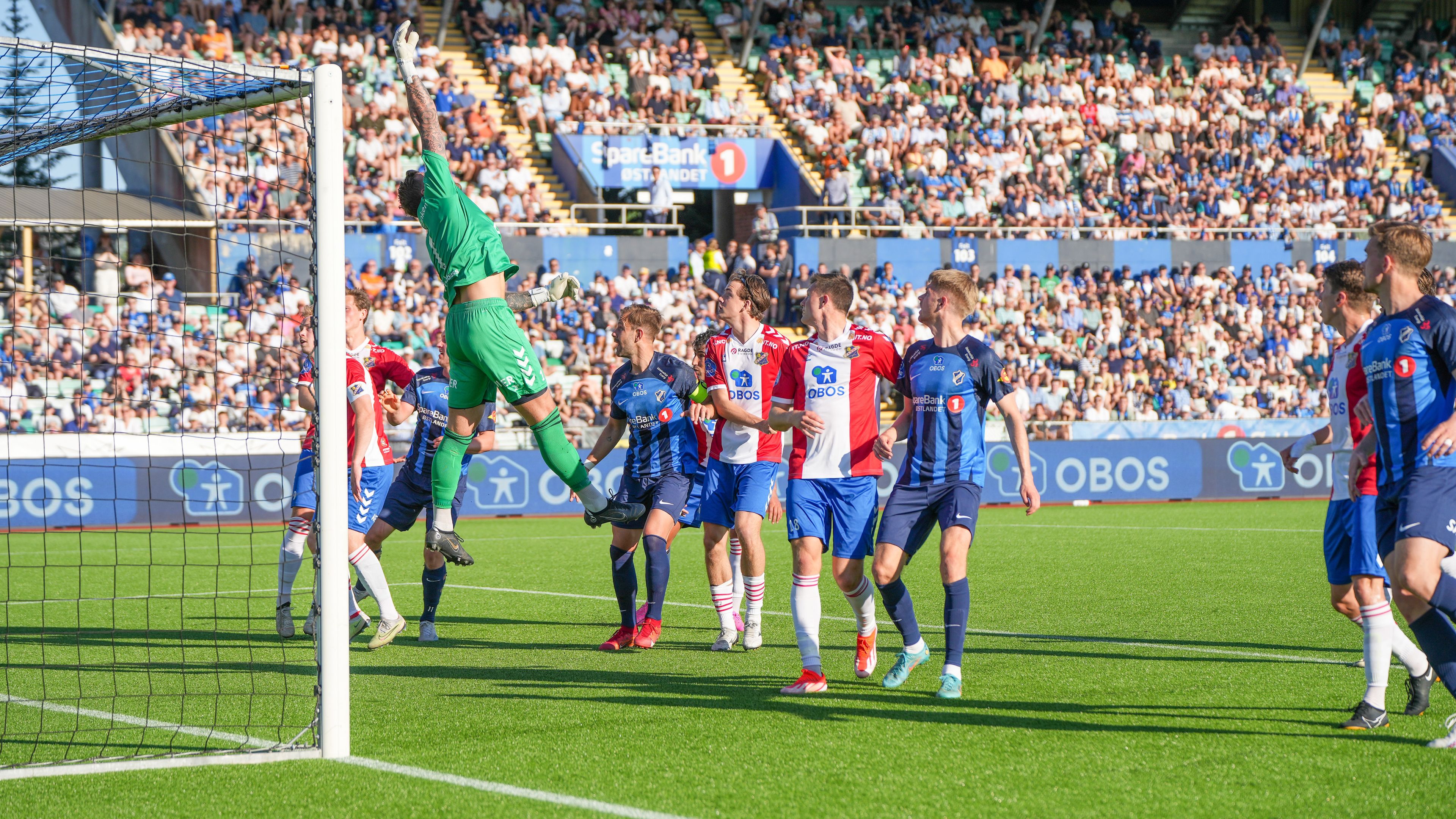 Foto av obos-ligaen i 2025 under en solfylt kampdag ved mållinja på stadion.