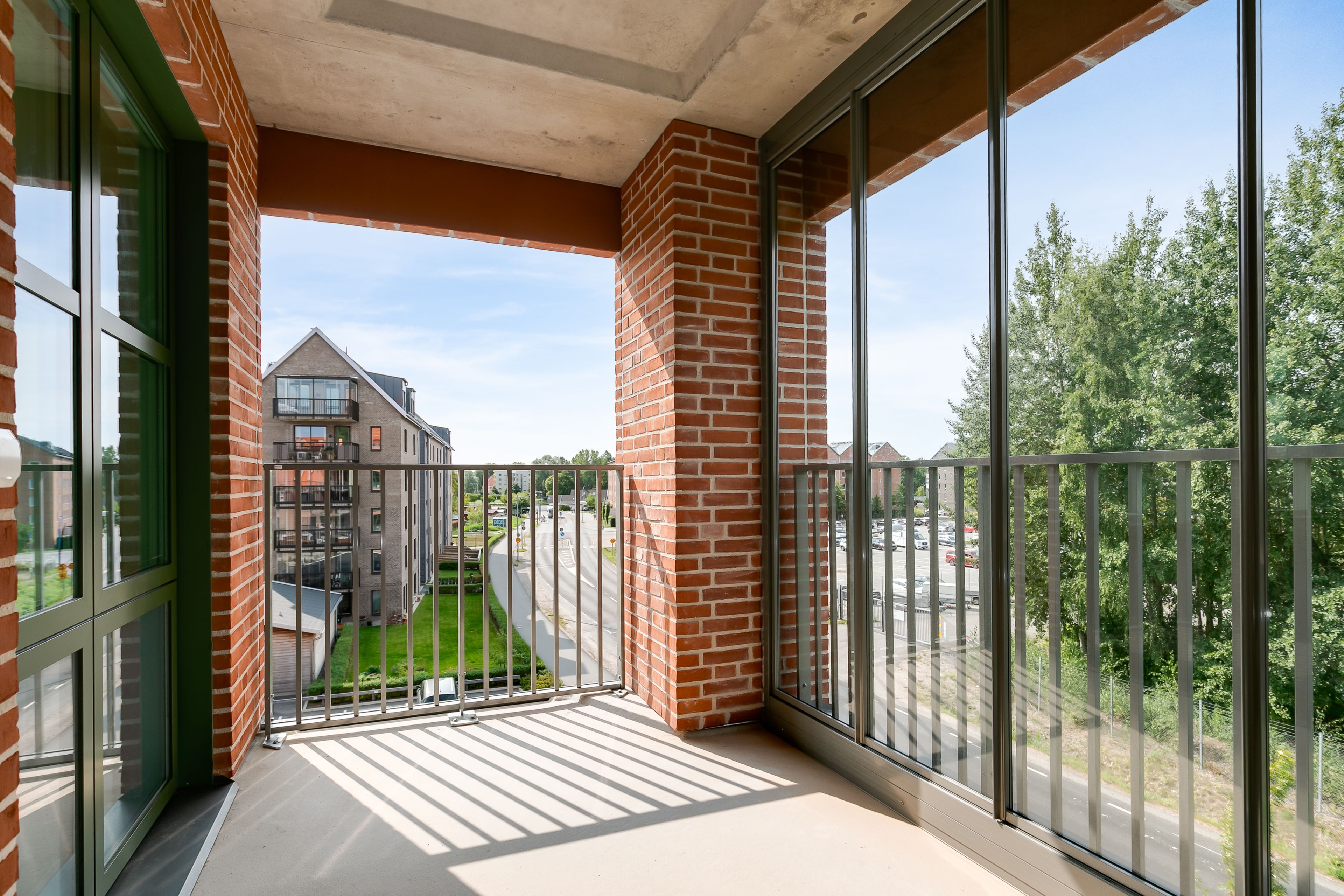 Foto på en balkong med glasväggar och grön utsikt