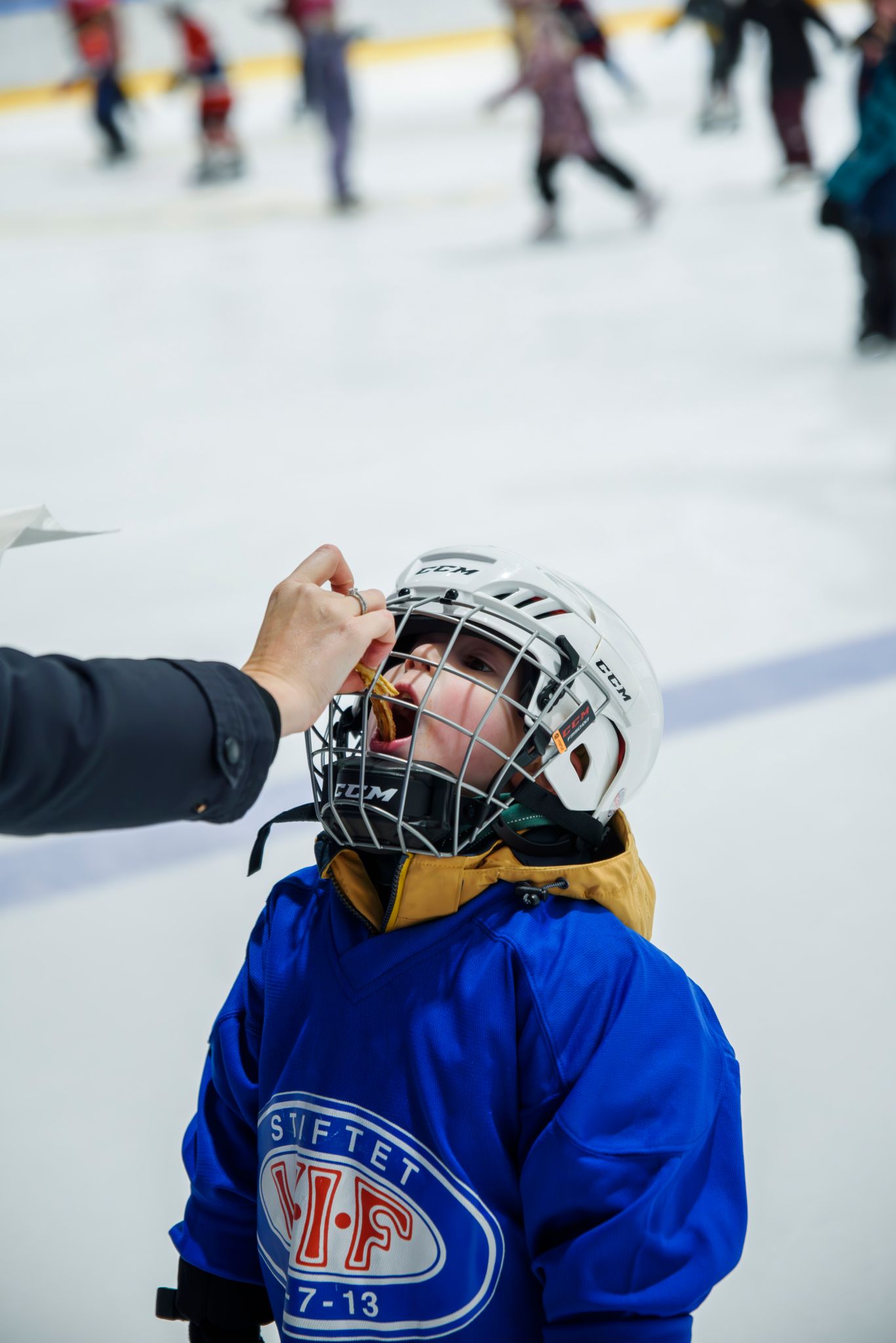 Foto av et barn som får litt påfyll av mat gjennom bekyttelsen på hjelmen.