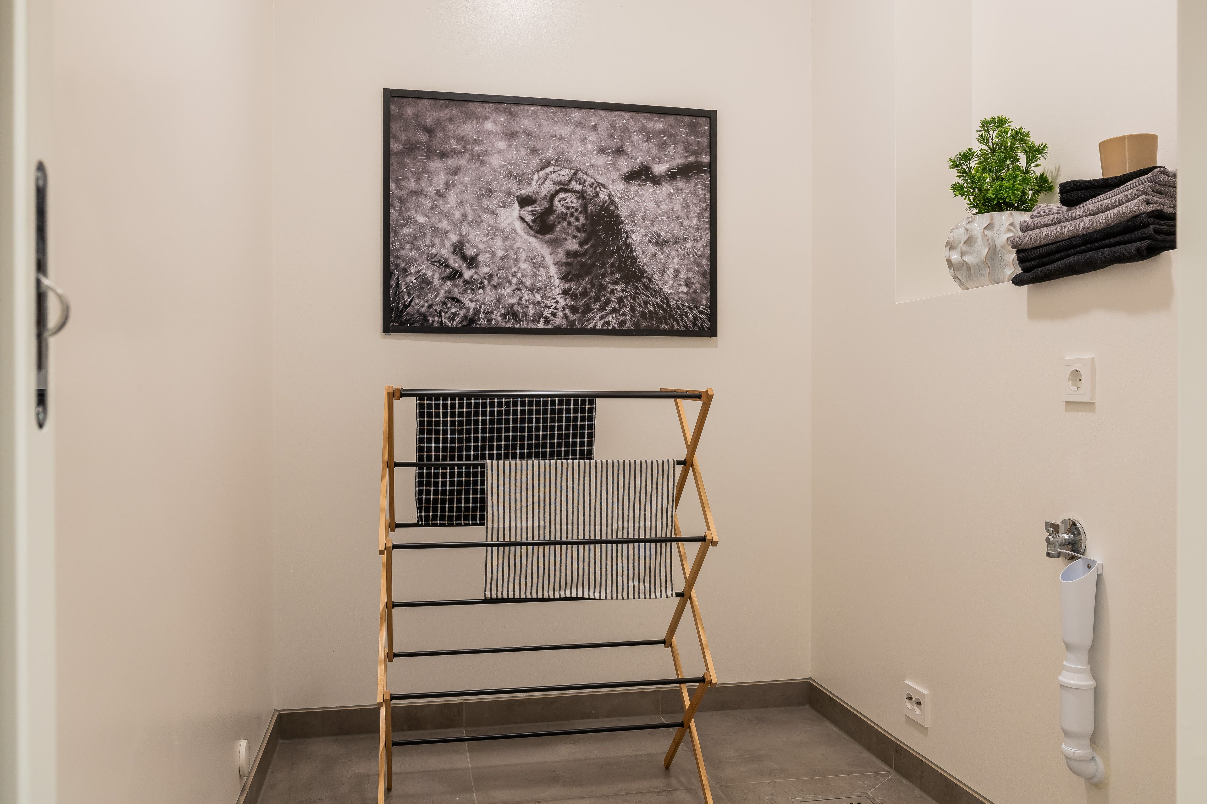 Foto av rom med tørkestativ og opplegg for vaskemaskin.