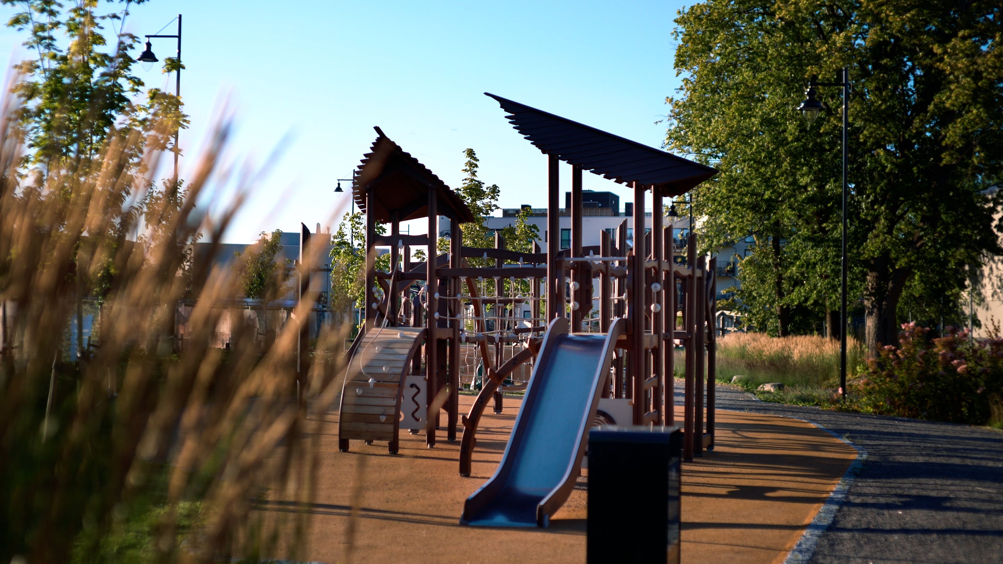 Lekeplass med leke- og klatrestativ i Teieparken, omgitt av grøntområder og gangvei.