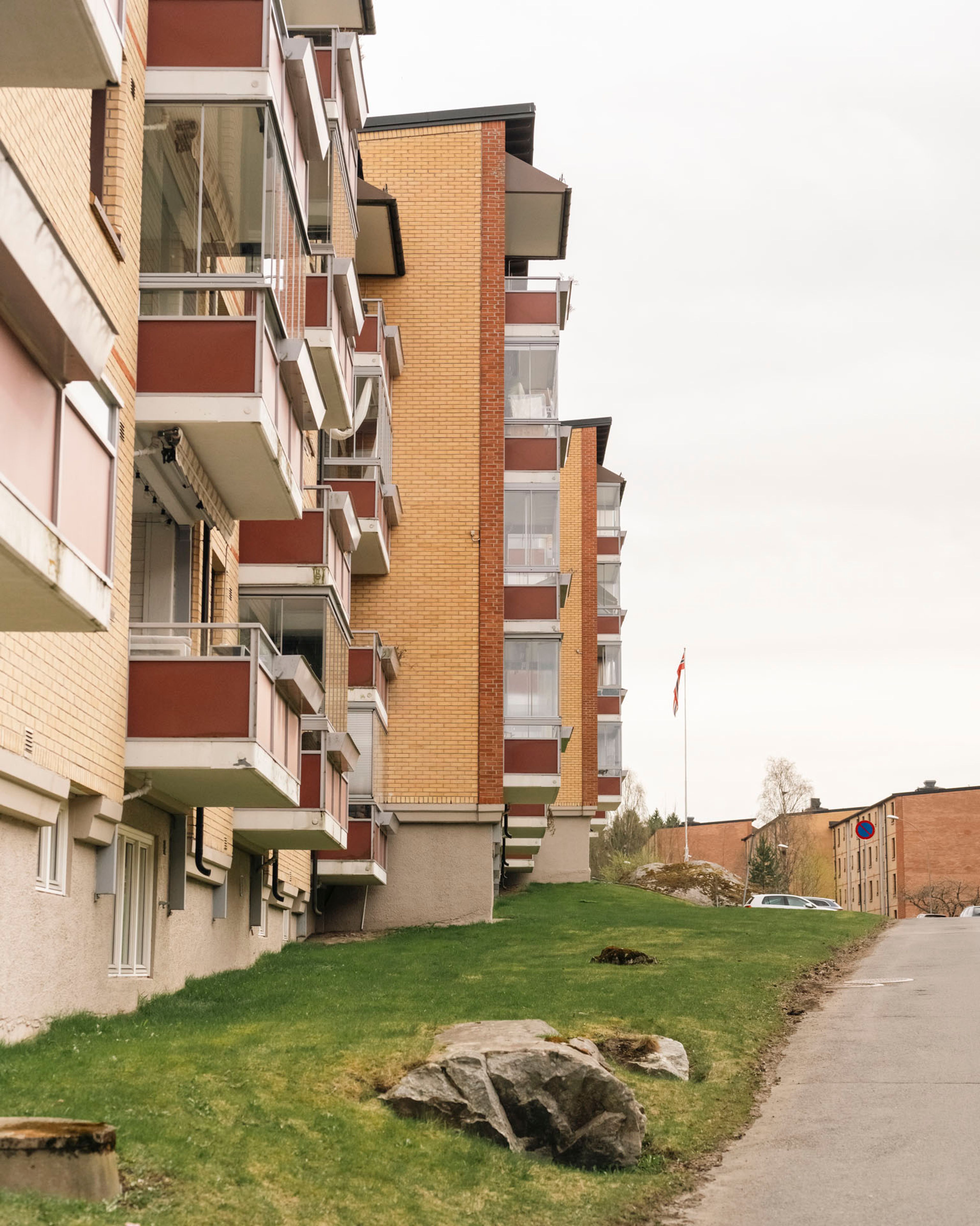 Fasaden av en av de 12 blokkene i Ulsrud borettslag, med karakteristiske røde balkongbrystninger på gul murstein.