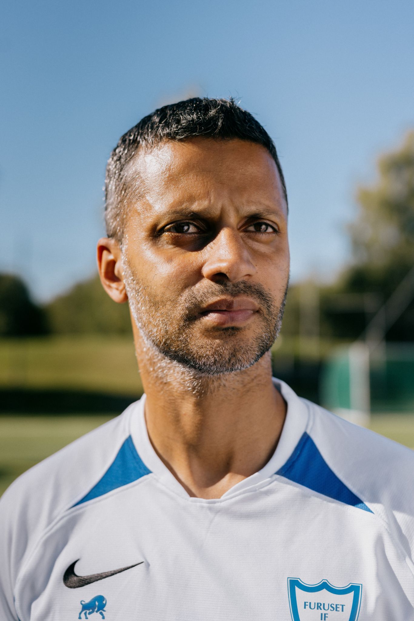 Nærbilde av Ghulam Abbas med fotballbane og mål i bakgrunnen.