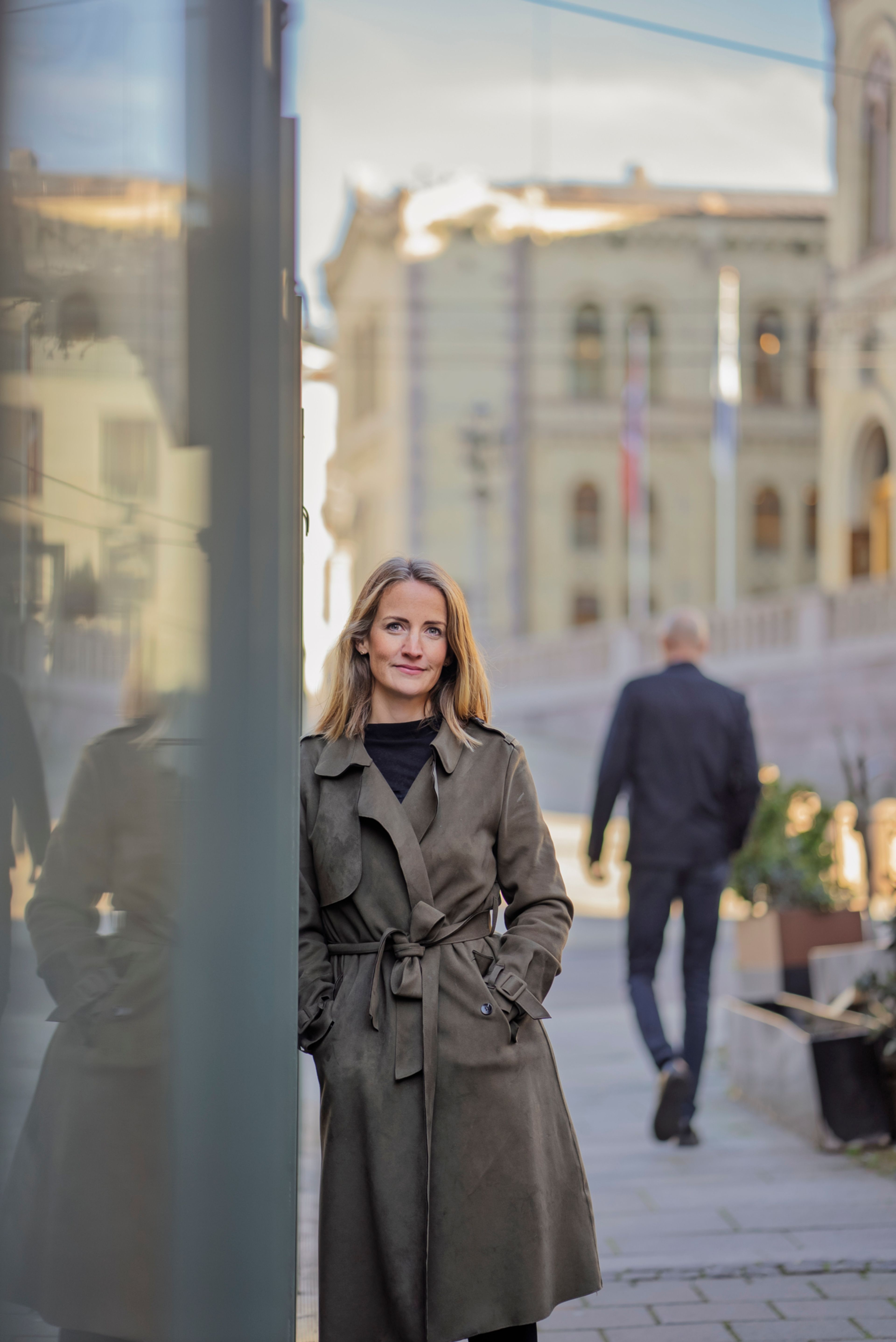 Ingjerd lener seg mot et butikkvindu på Karl Johan med Stortinget liggende i bakgrunnen.