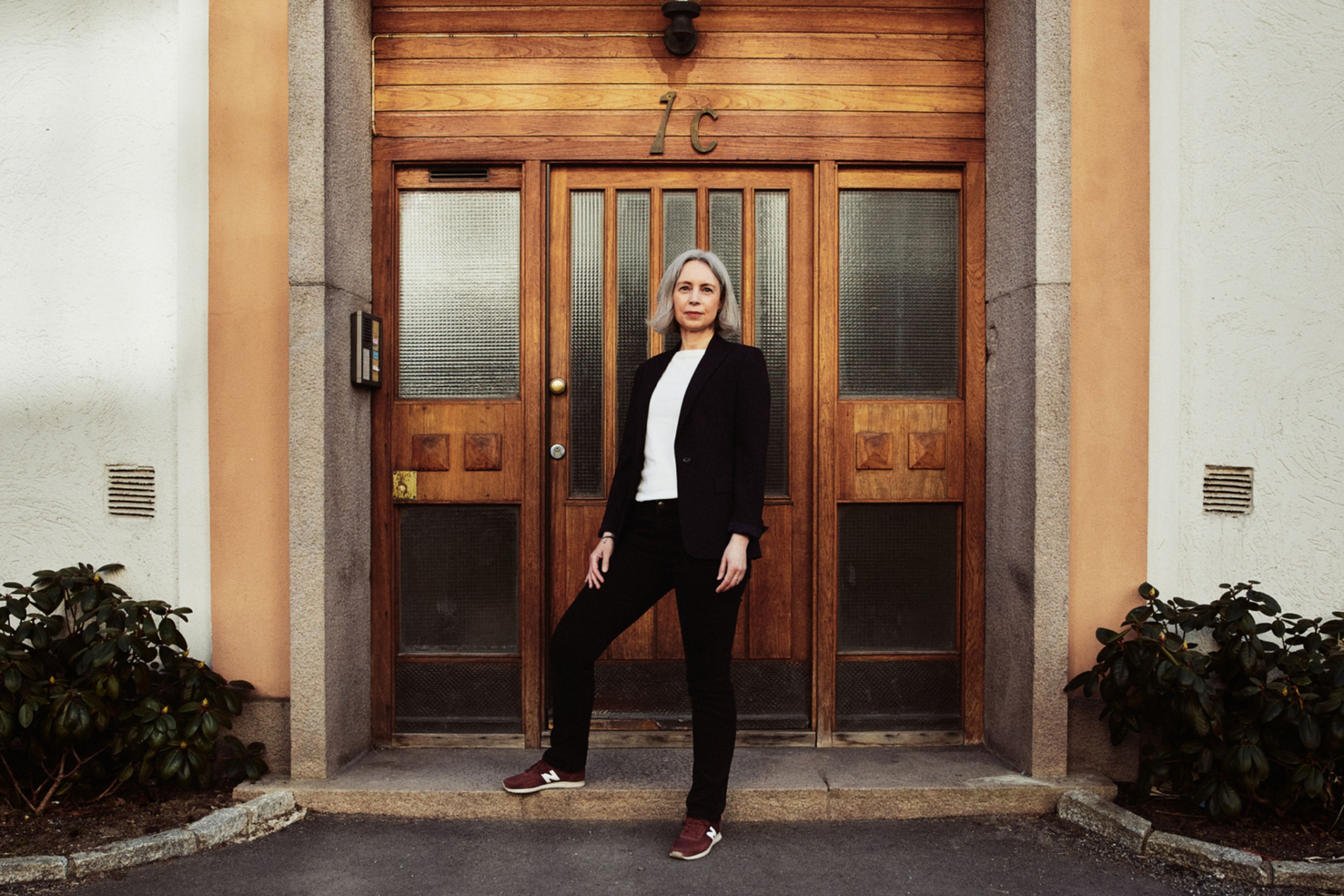 Anne-Kristine Kronborg ved inngangsdøren til en boligblokk.