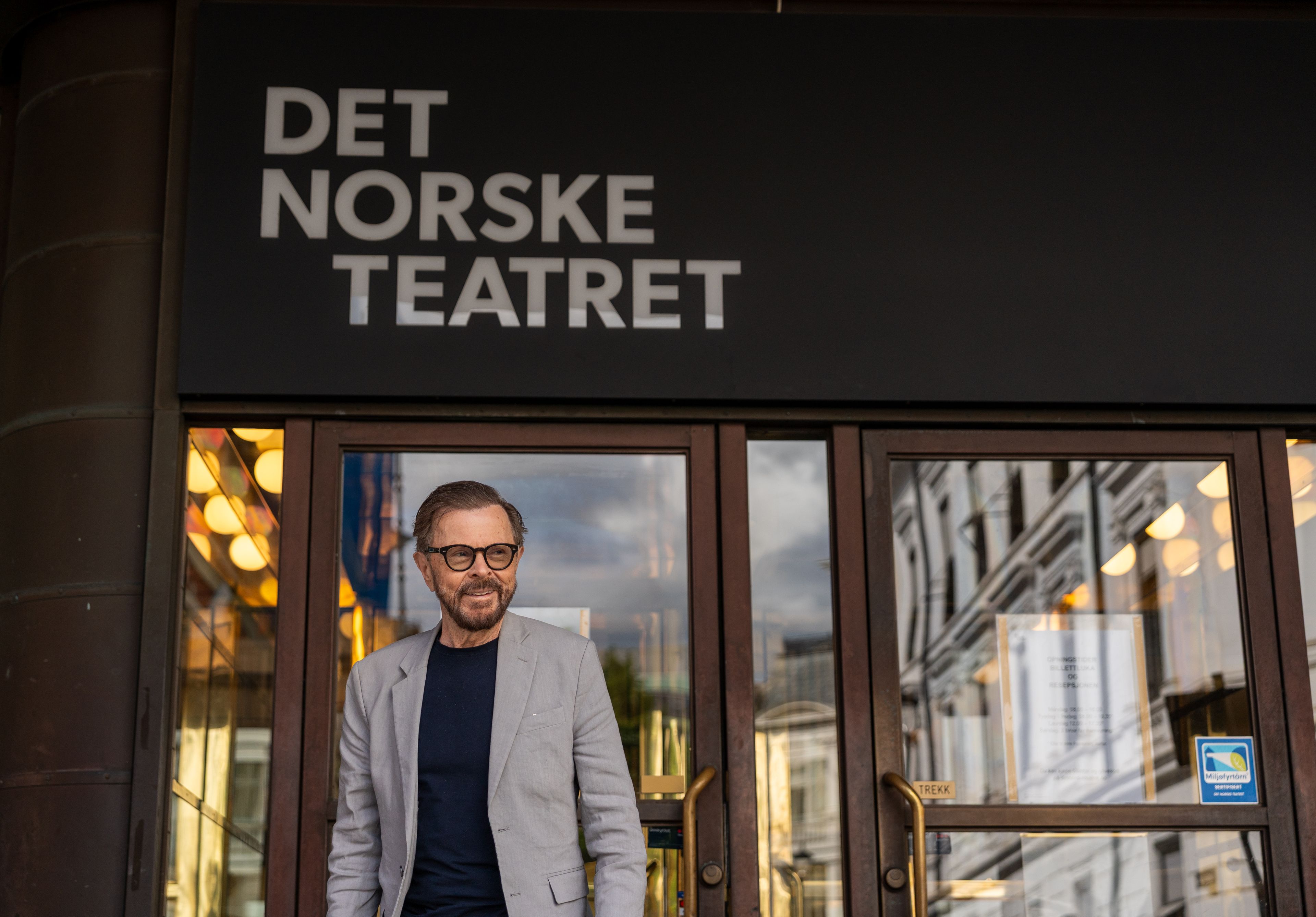 Björn Ulvaeus står i inngangspartiet til Det Norske Teatret, under den store skiltteksten med teaterets navn.