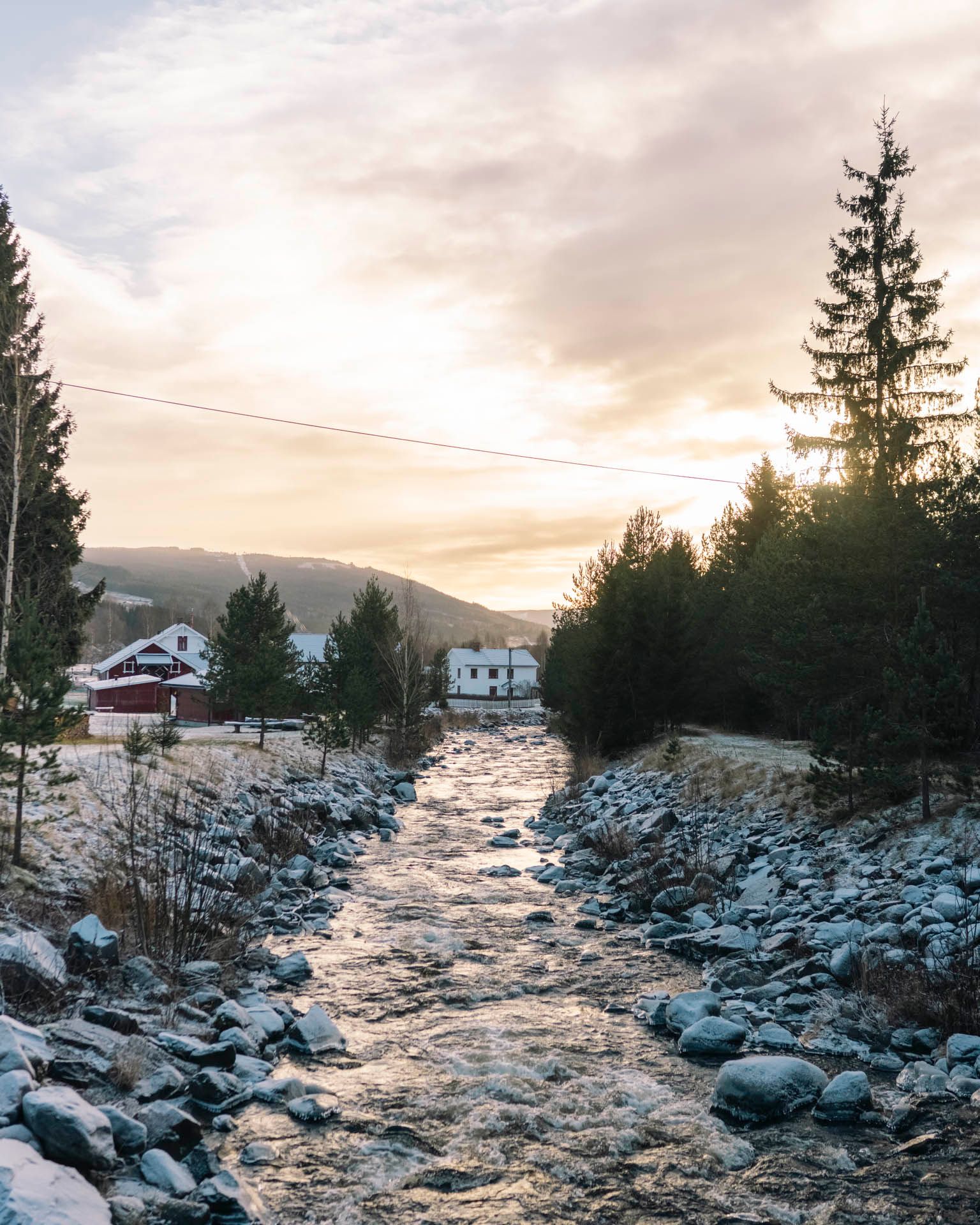 Bekk i fjellområde med snø langs breddene og vinterlige forhold rundt bebyggelse.