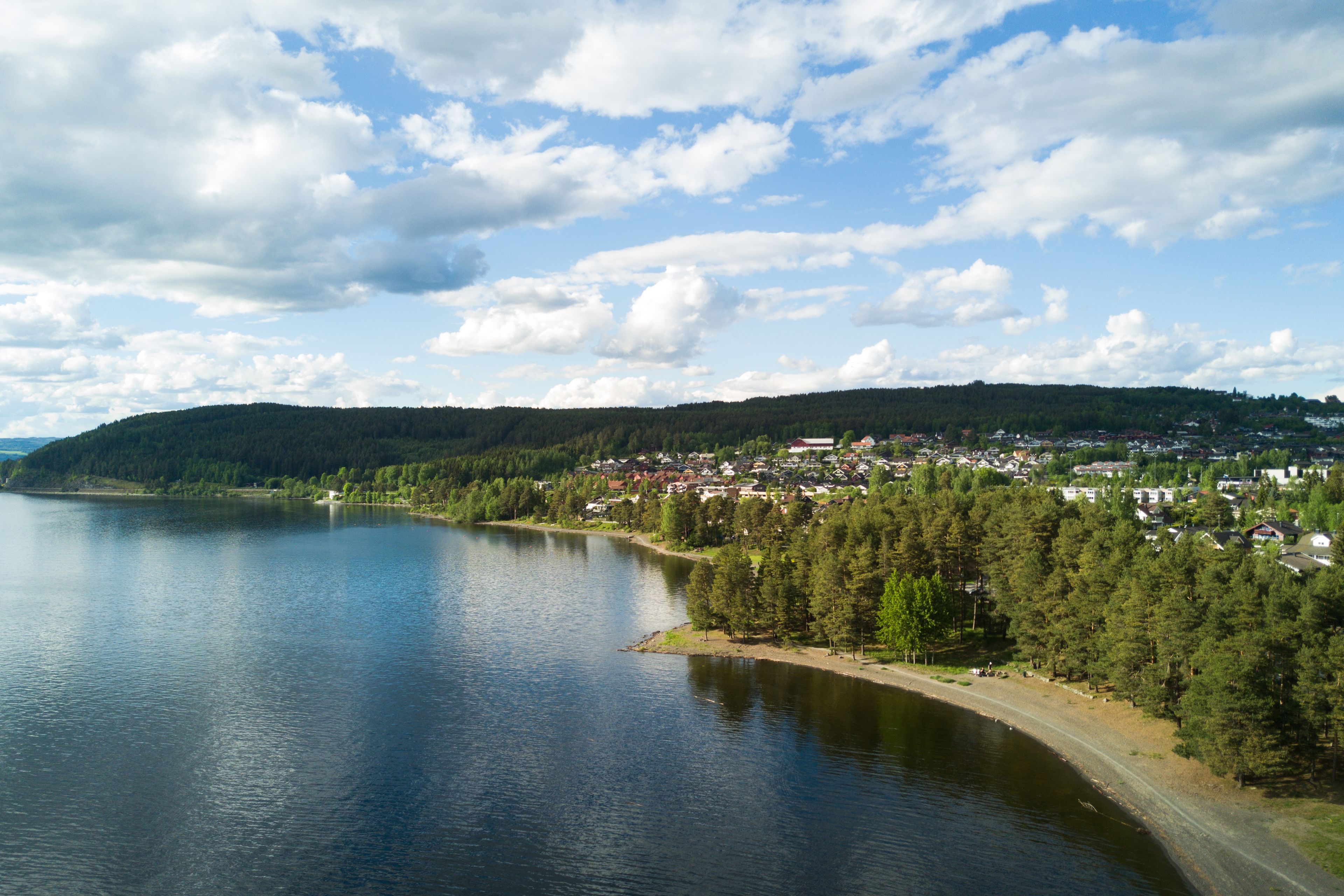 Badeplass med strandlinje ved Mjøsa på dagtid, sett ovenfra